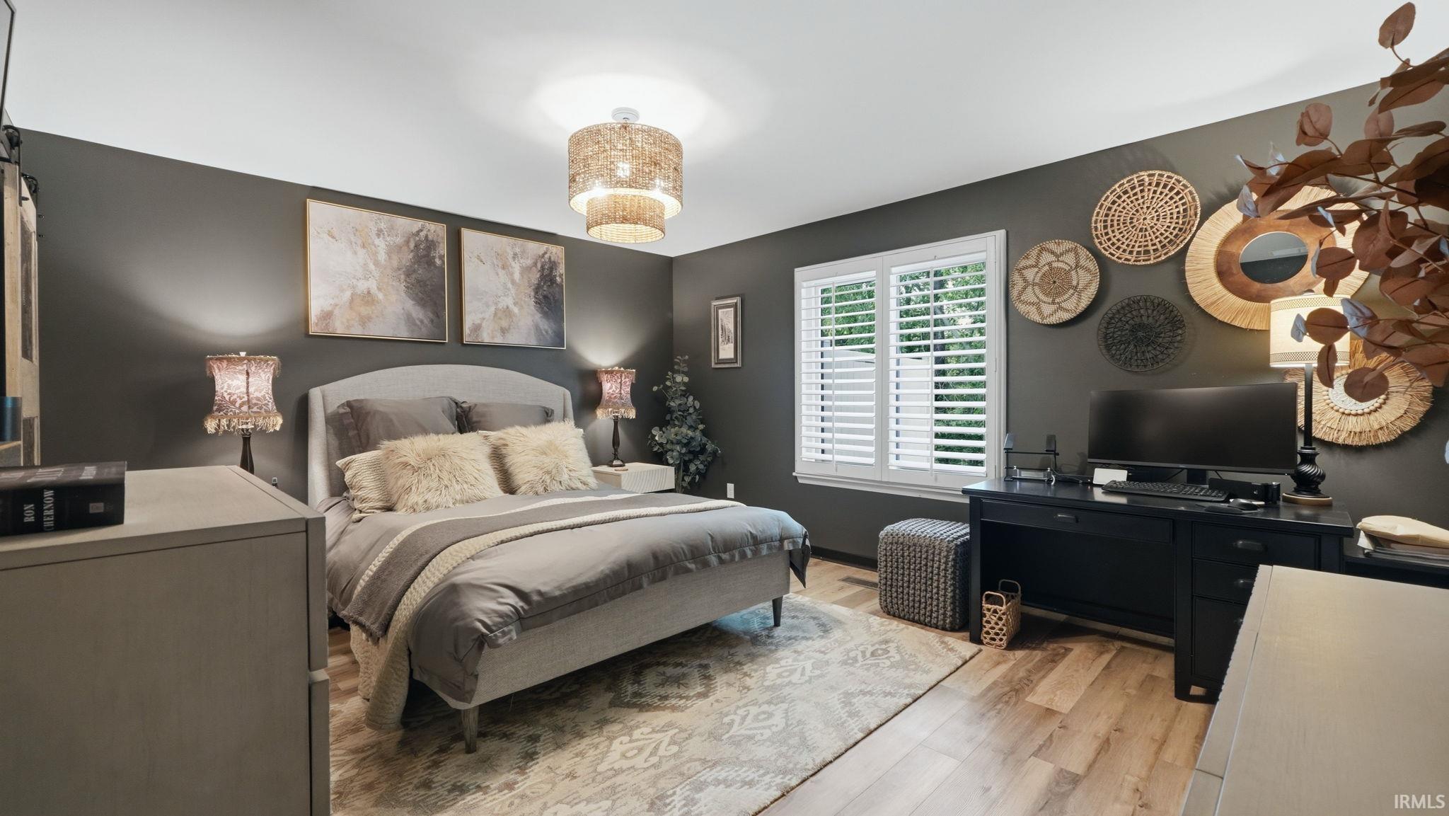 Spacious room featuring wood-finish flooring, a contemporary ceiling light fixture, and a window with white plantation shutters
