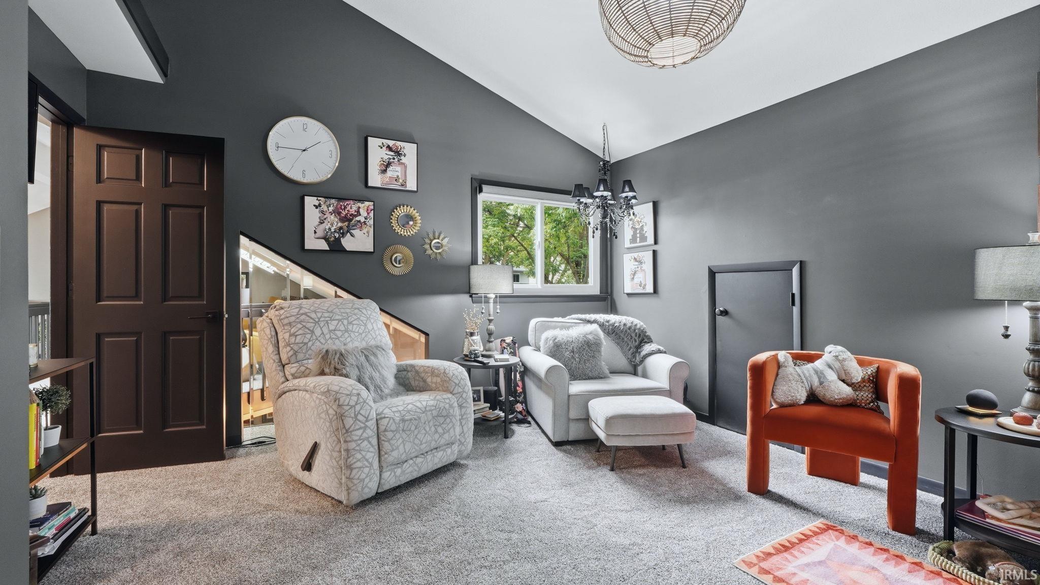 Carpeted room featuring a dark paneled door, a window with natural light, and a built-in storage nook under the stairs