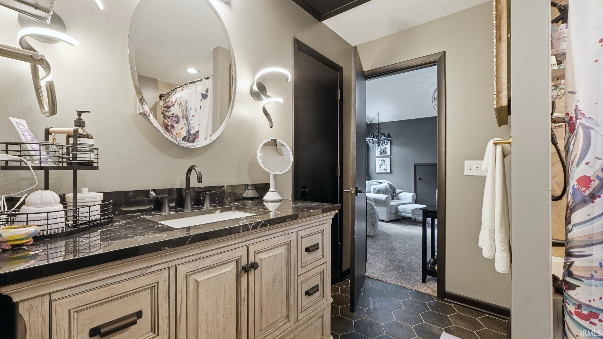 Bathroom featuring a light wood-finish vanity with a dark countertop, an undermount sink, and a dark faucet