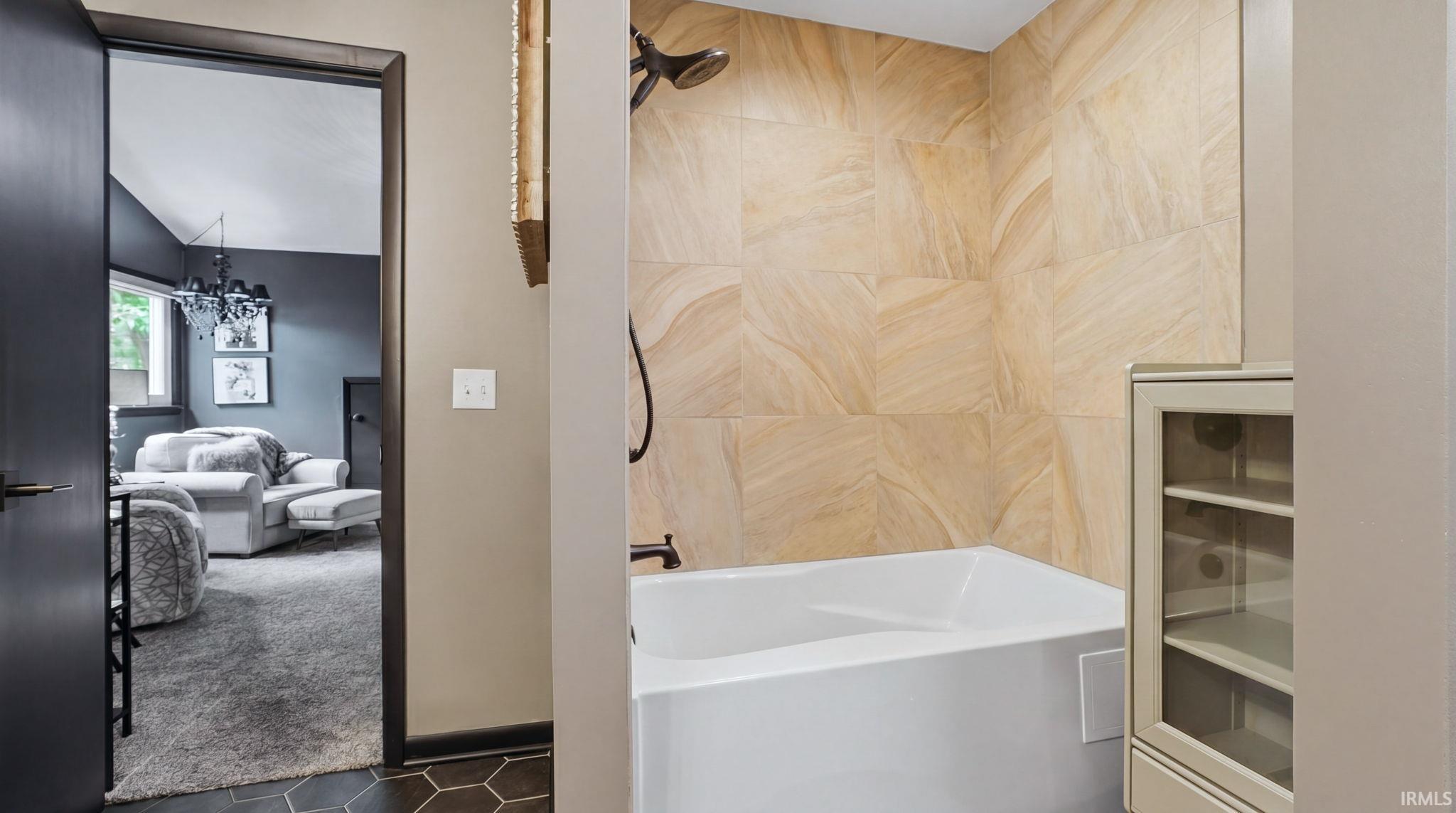 Bathtub with textured tile surround and a dark bronze shower fixture
