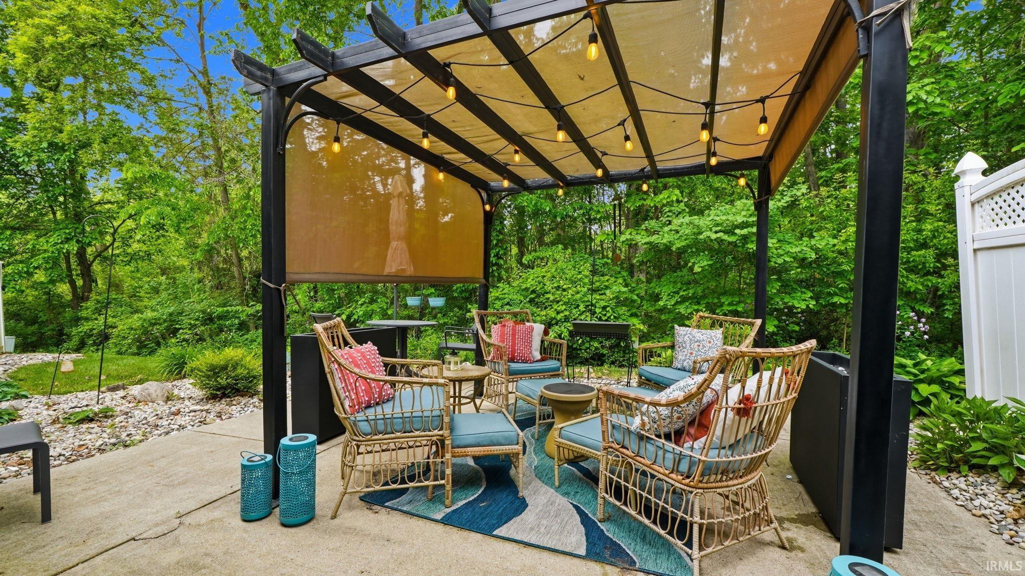 Patio area featuring a permanent pergola with string lighting and a retractable shade