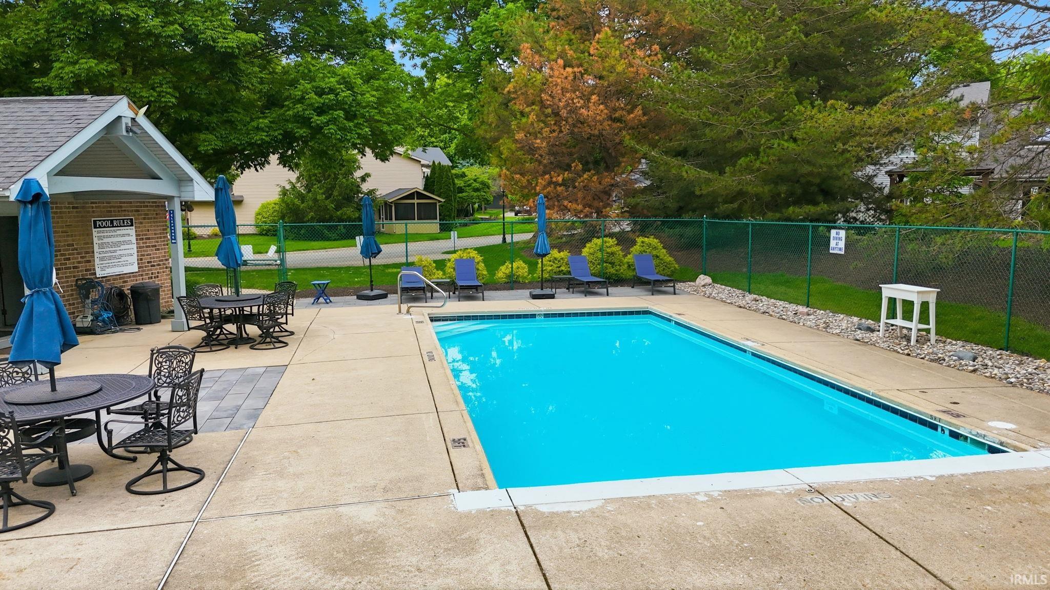 Outdoor swimming pool with a concrete surround, adjacent patio space, and a brick pool house
