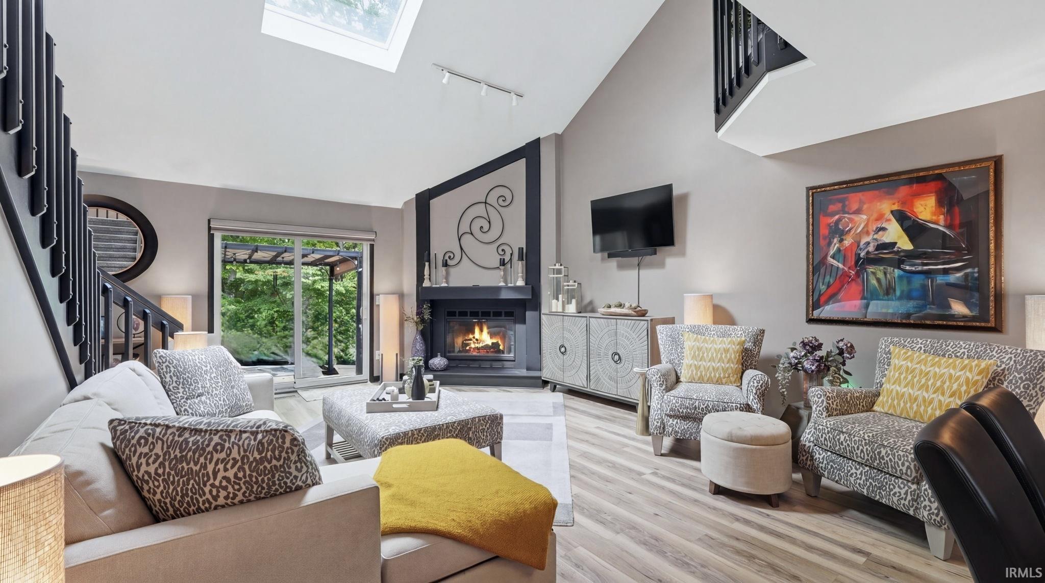 Living area featuring vaulted ceilings, a skylight, and wood-finish flooring