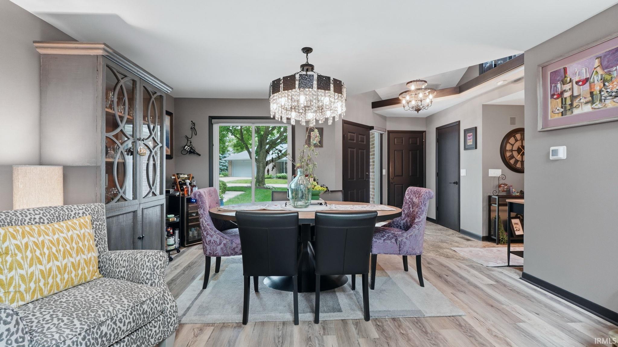 Open-concept living space with light wood-finish flooring, a contemporary chandelier, built-in display cabinetry, and a sliding glass door