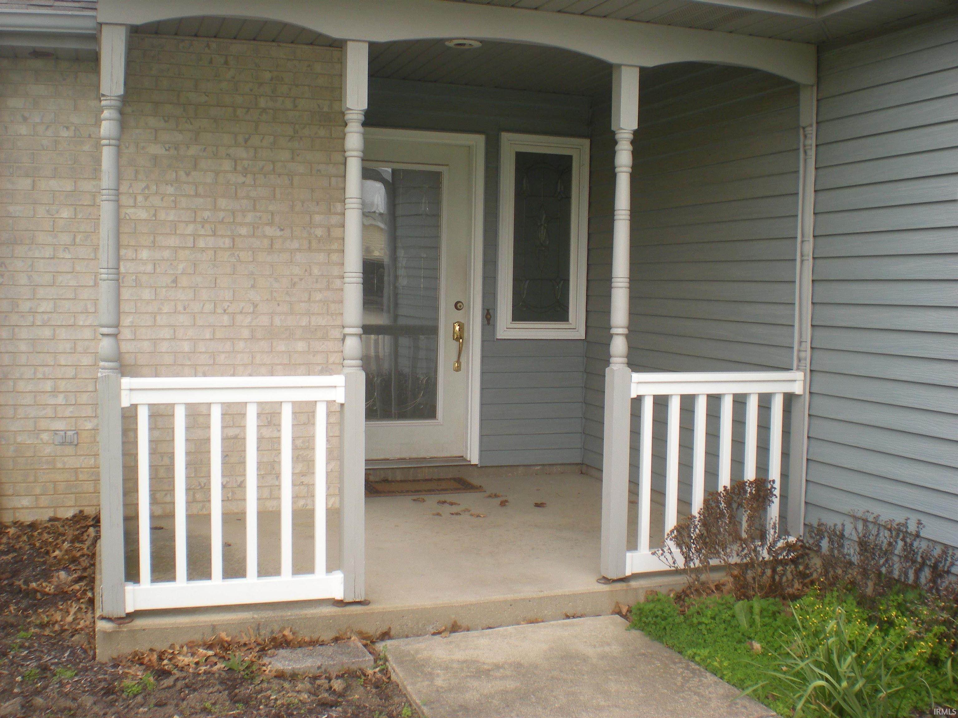 Covered front entry featuring a white paneled door with glass insert, sidelight, and brass-tone hardware