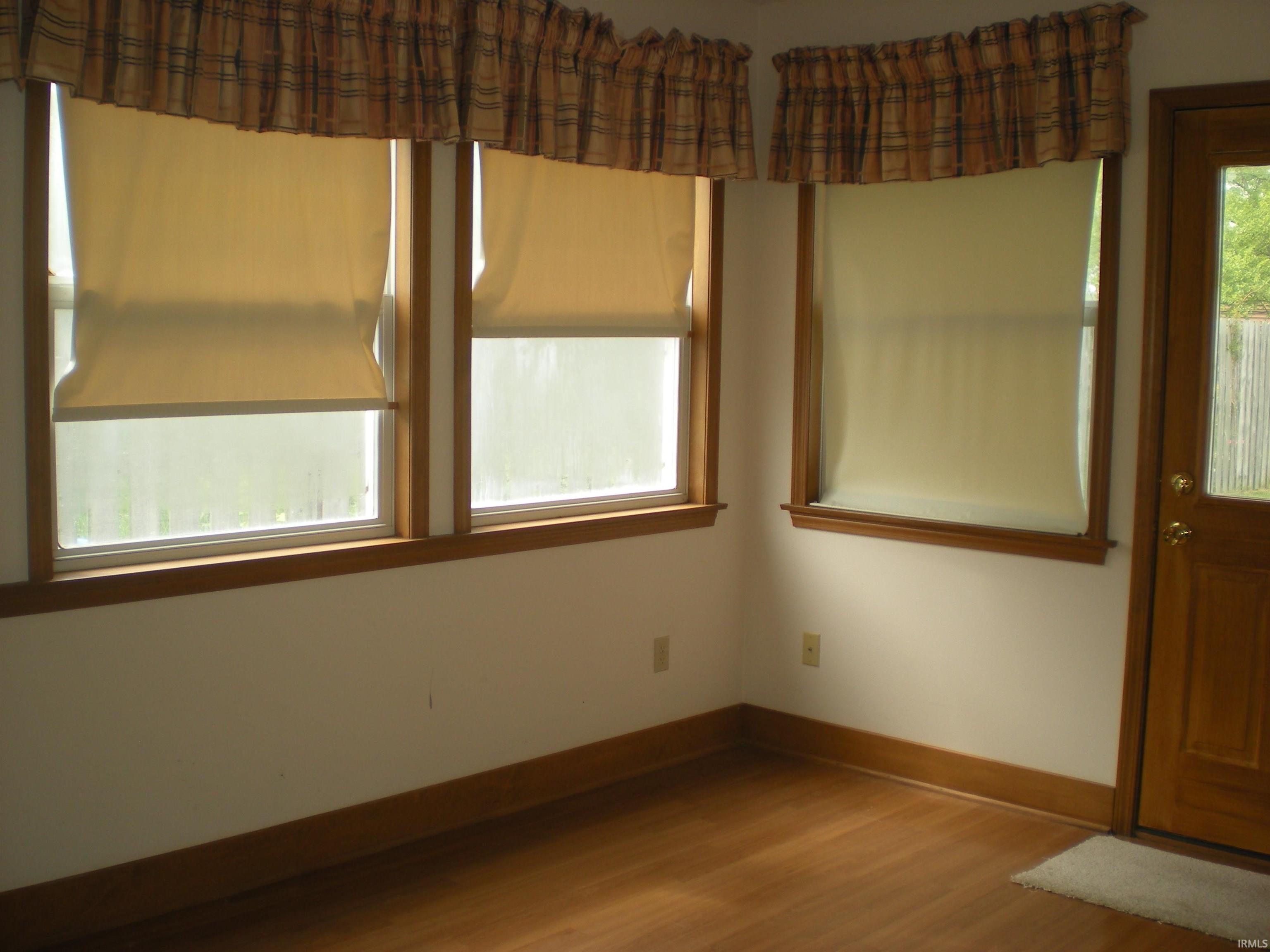 Room featuring wood-finish flooring, white walls, and light-toned wood trim