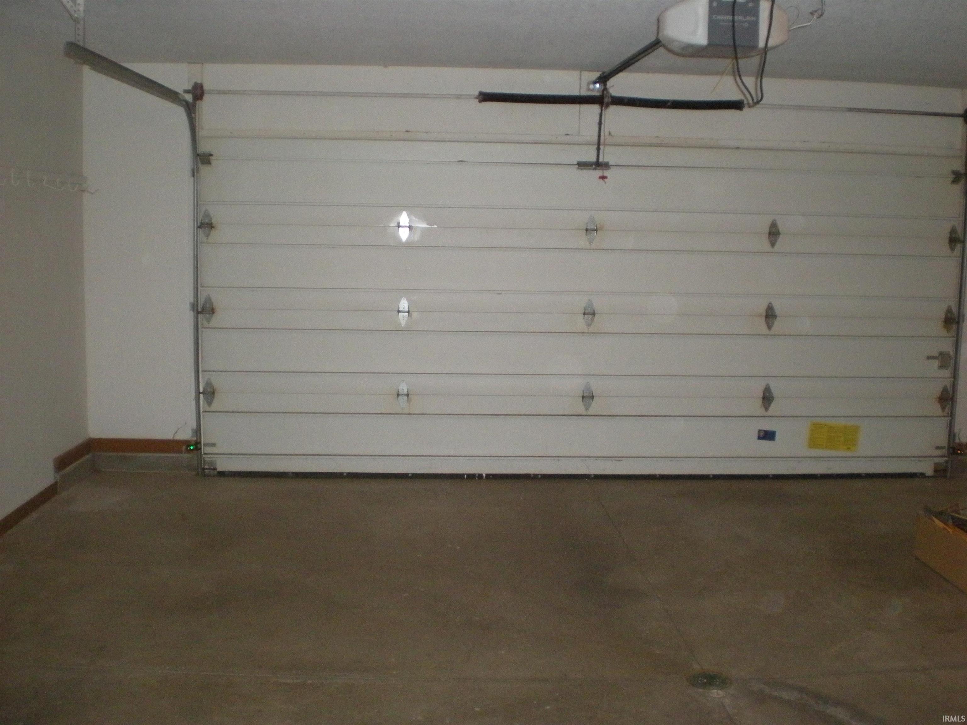 Spacious garage featuring a white sectional garage door with decorative hardware and an automatic opener