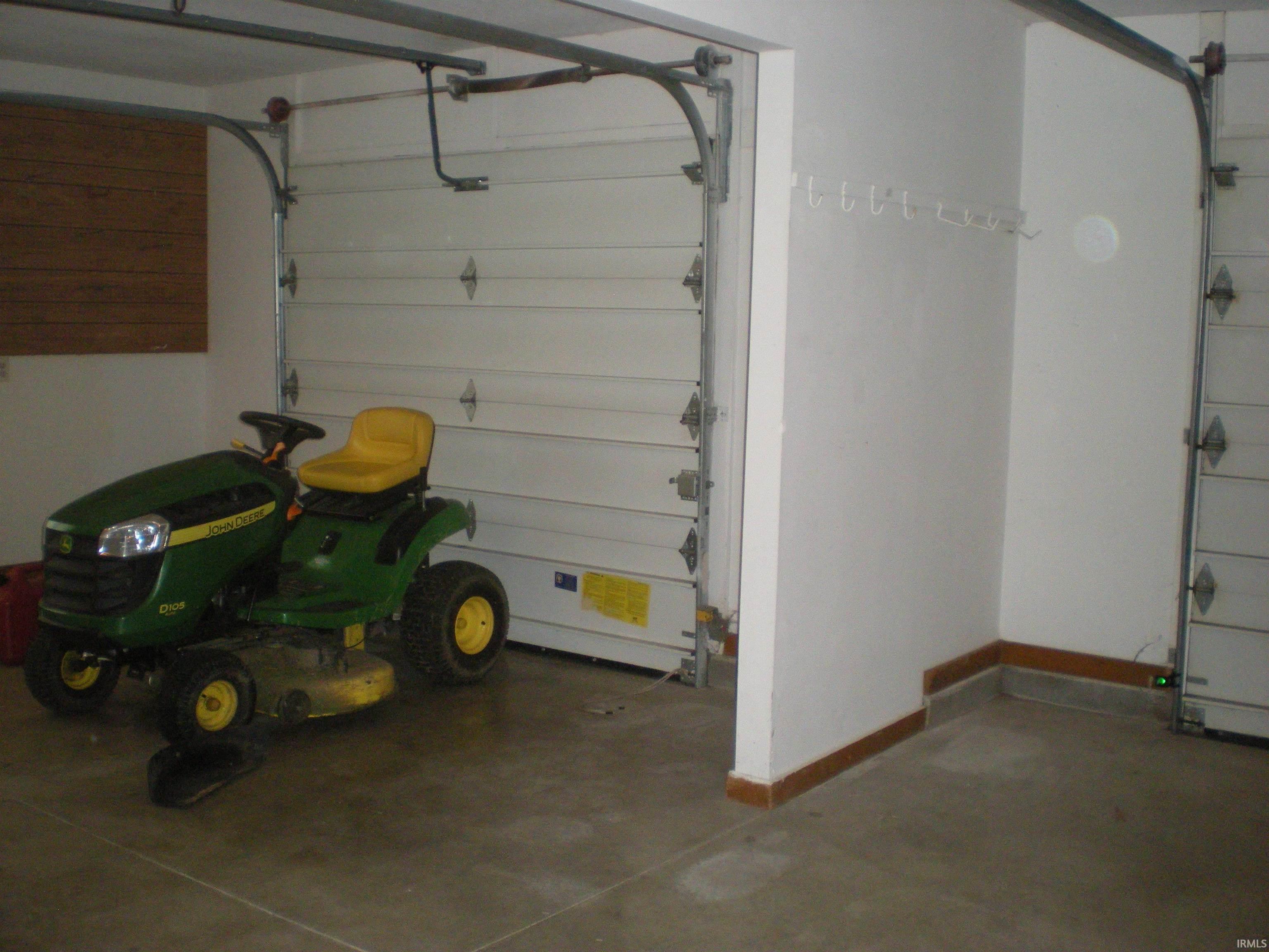 Garage space featuring two sectional overhead doors, concrete flooring, and an interior wood-paneled accent wall
