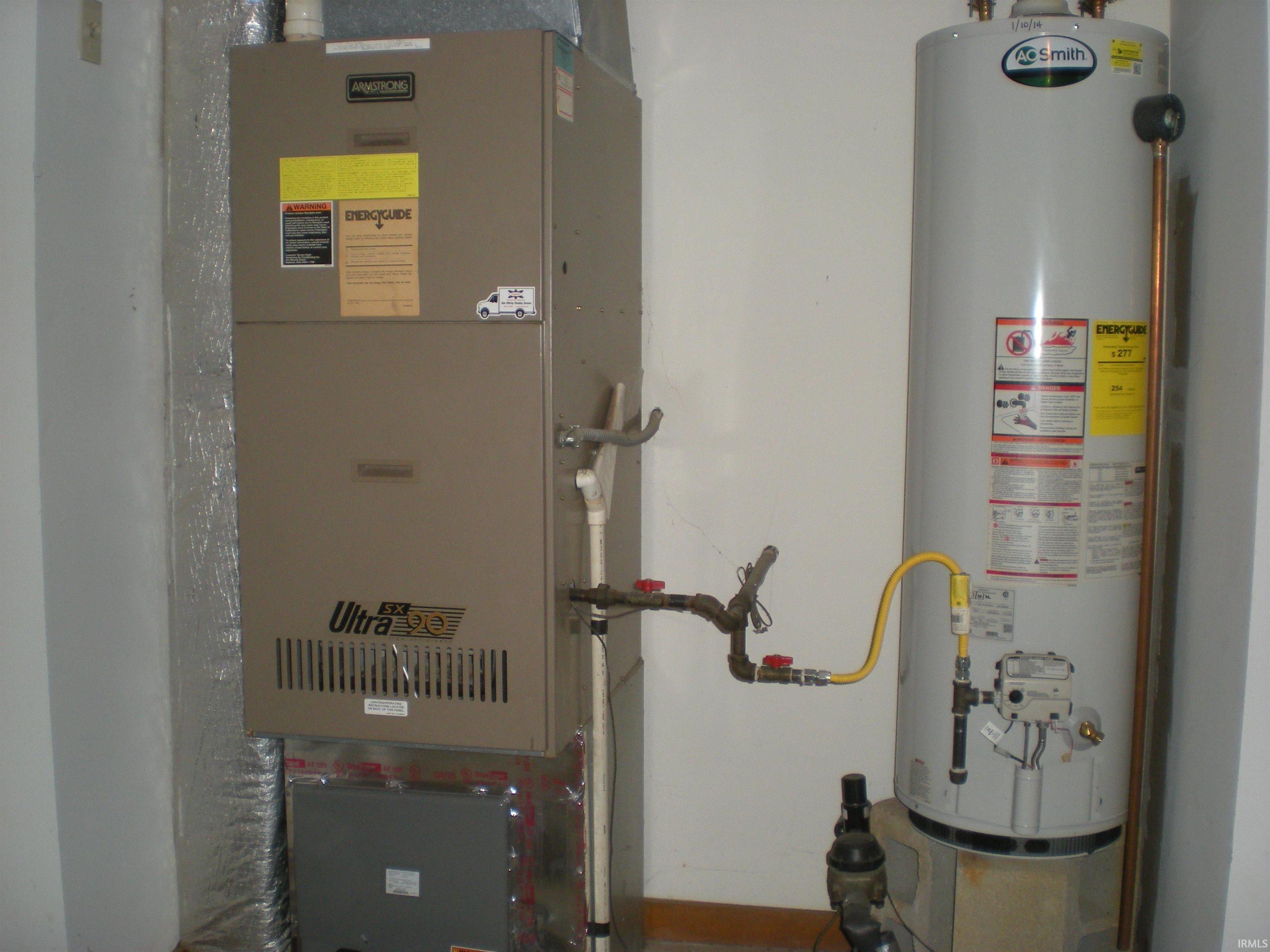 Mechanical room featuring a water heater and furnace with exposed ductwork