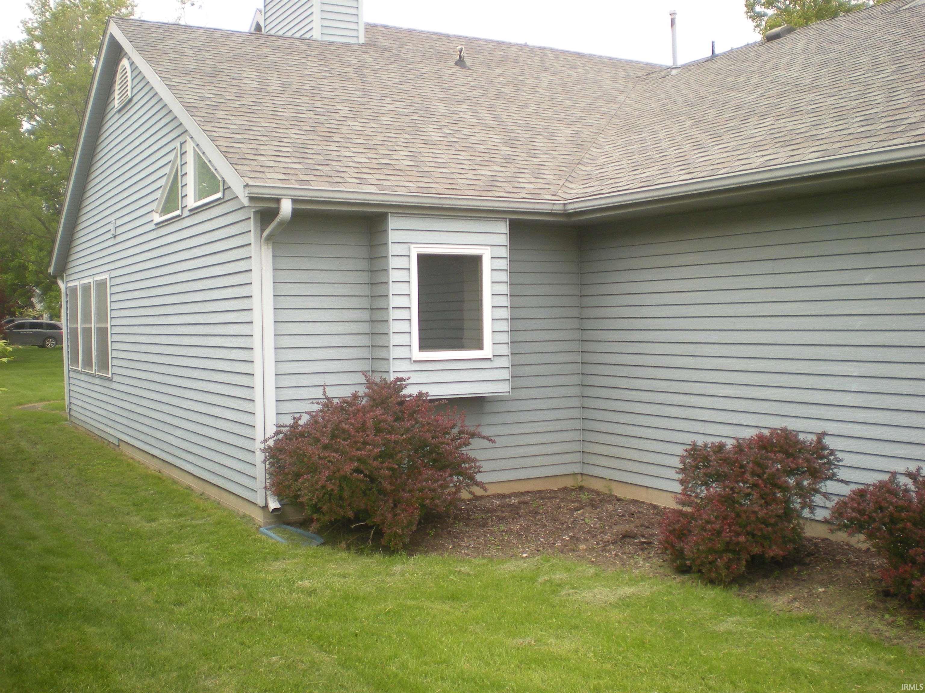 Exterior featuring light blue horizontal siding, a shingled roof, white framed windows, and green lawn