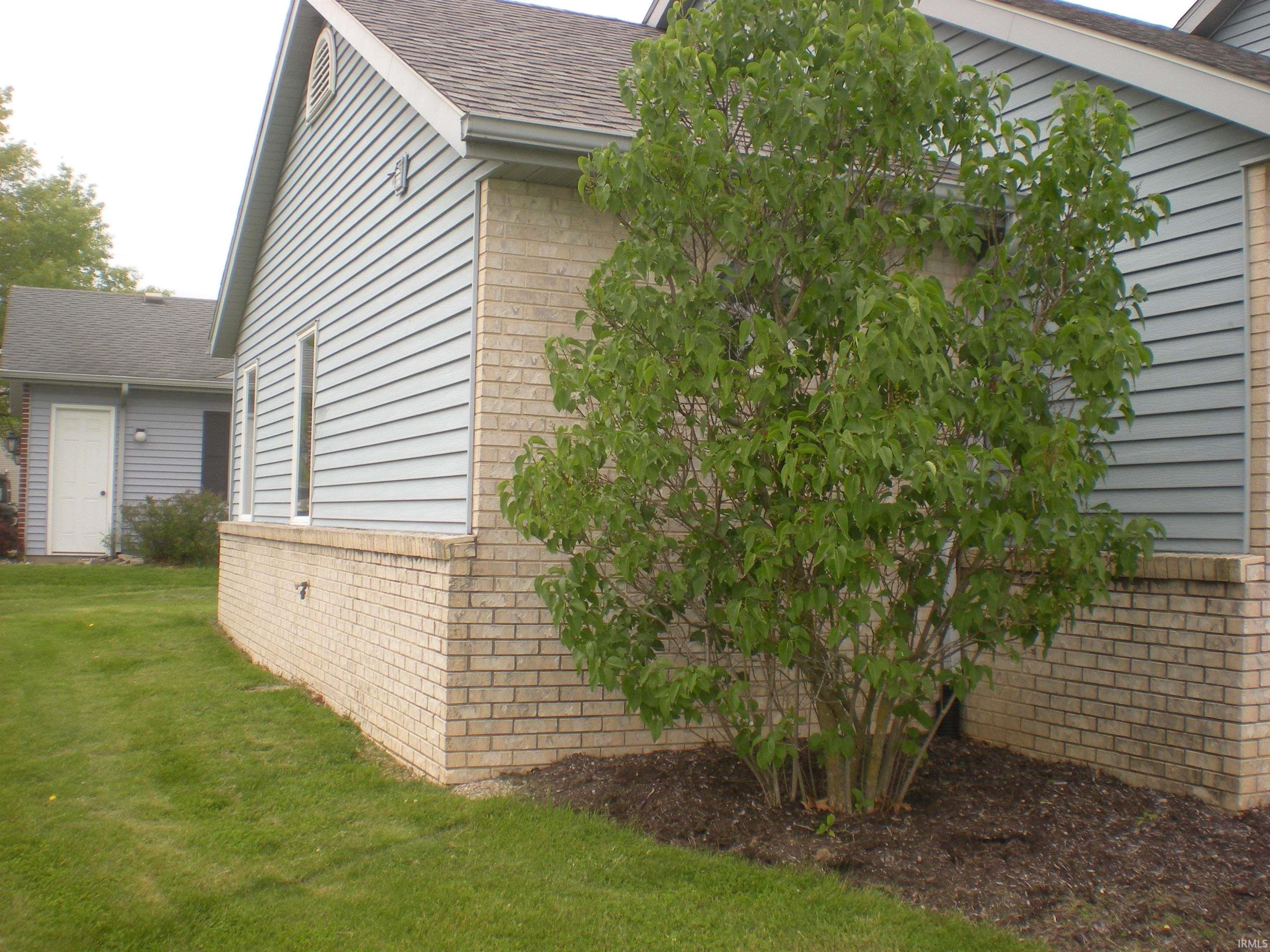 Exterior featuring light-toned brickwork, horizontal siding, and a gabled roofline