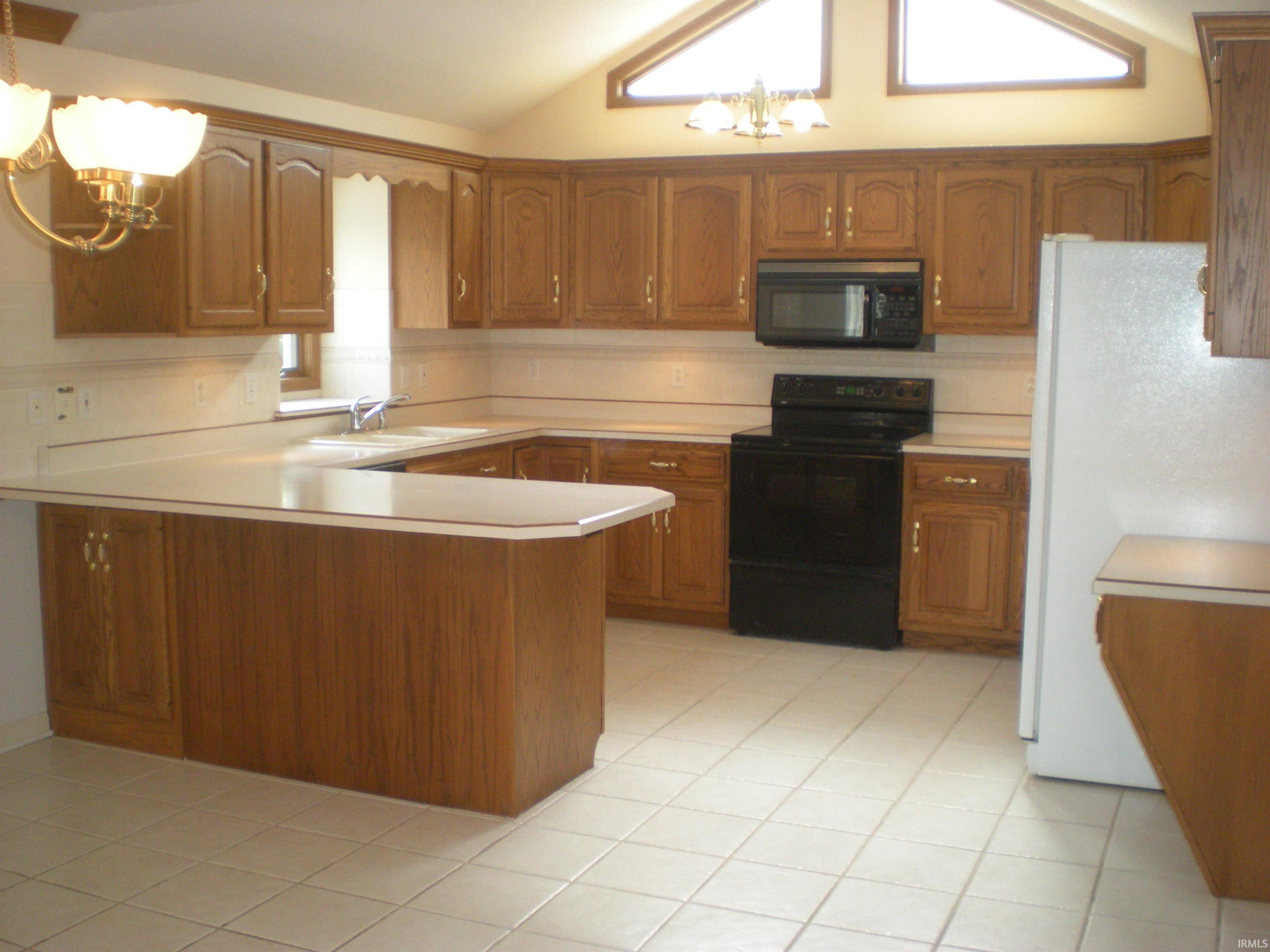 Kitchen featuring wood-finish cabinetry, light-toned countertops, and a full suite of appliances