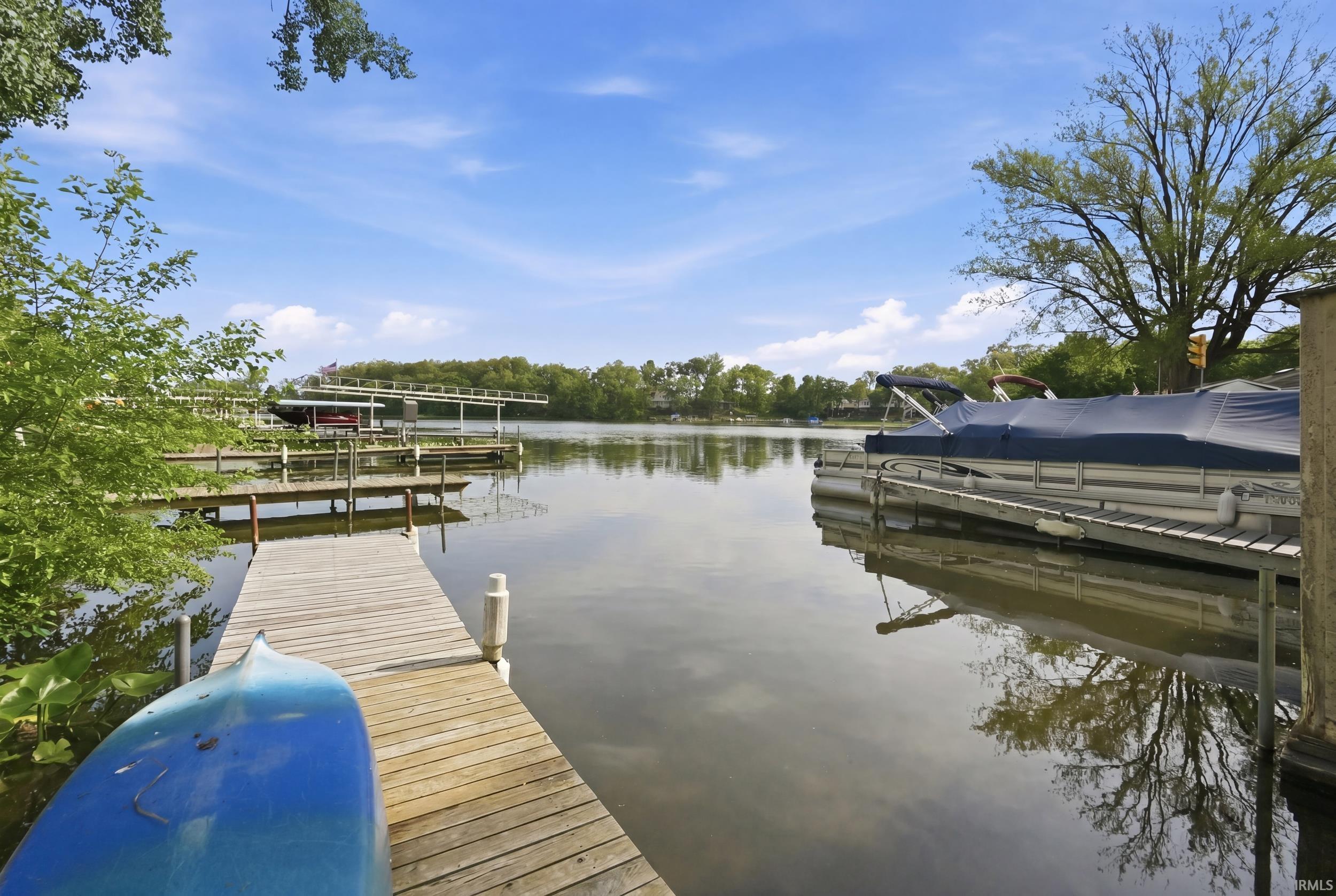 Waterfront property featuring a wooden dock, multiple boat slips, and mature surrounding trees