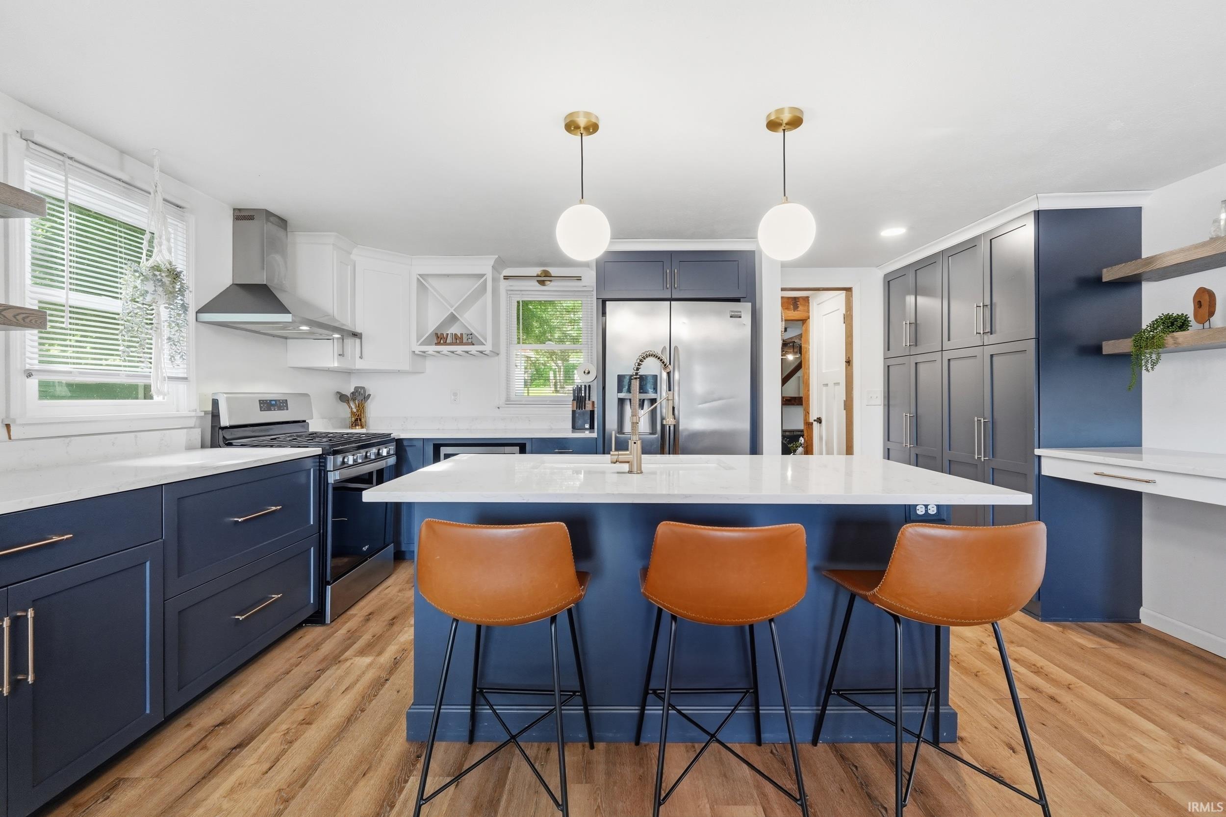 Kitchen featuring a central island with countertop seating, wood-finish flooring, stainless steel appliances, and two-tone cabinetry with ample storage