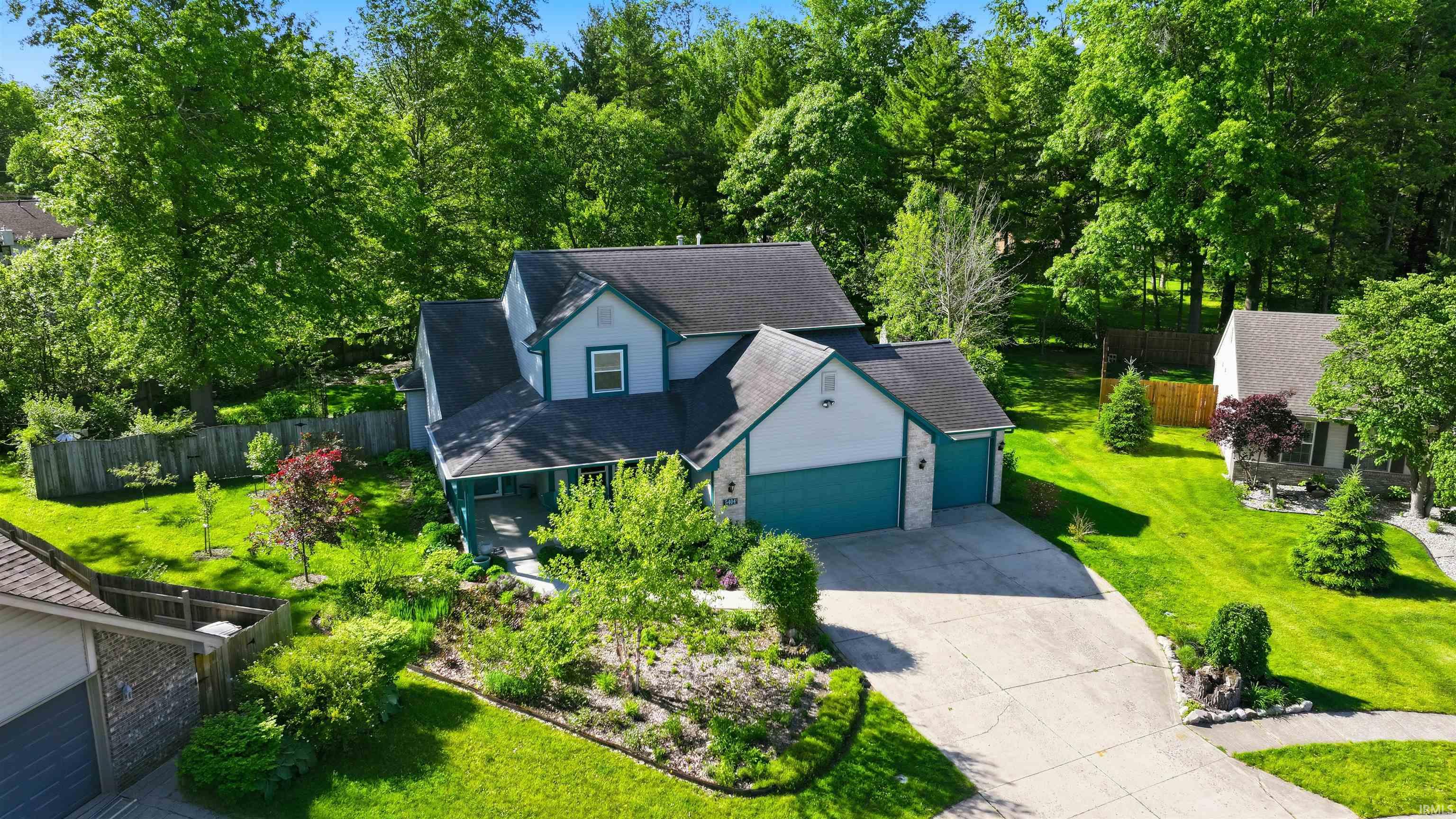Two-story residence with a light blue and white exterior, featuring a dark shingle roof and a covered front porch