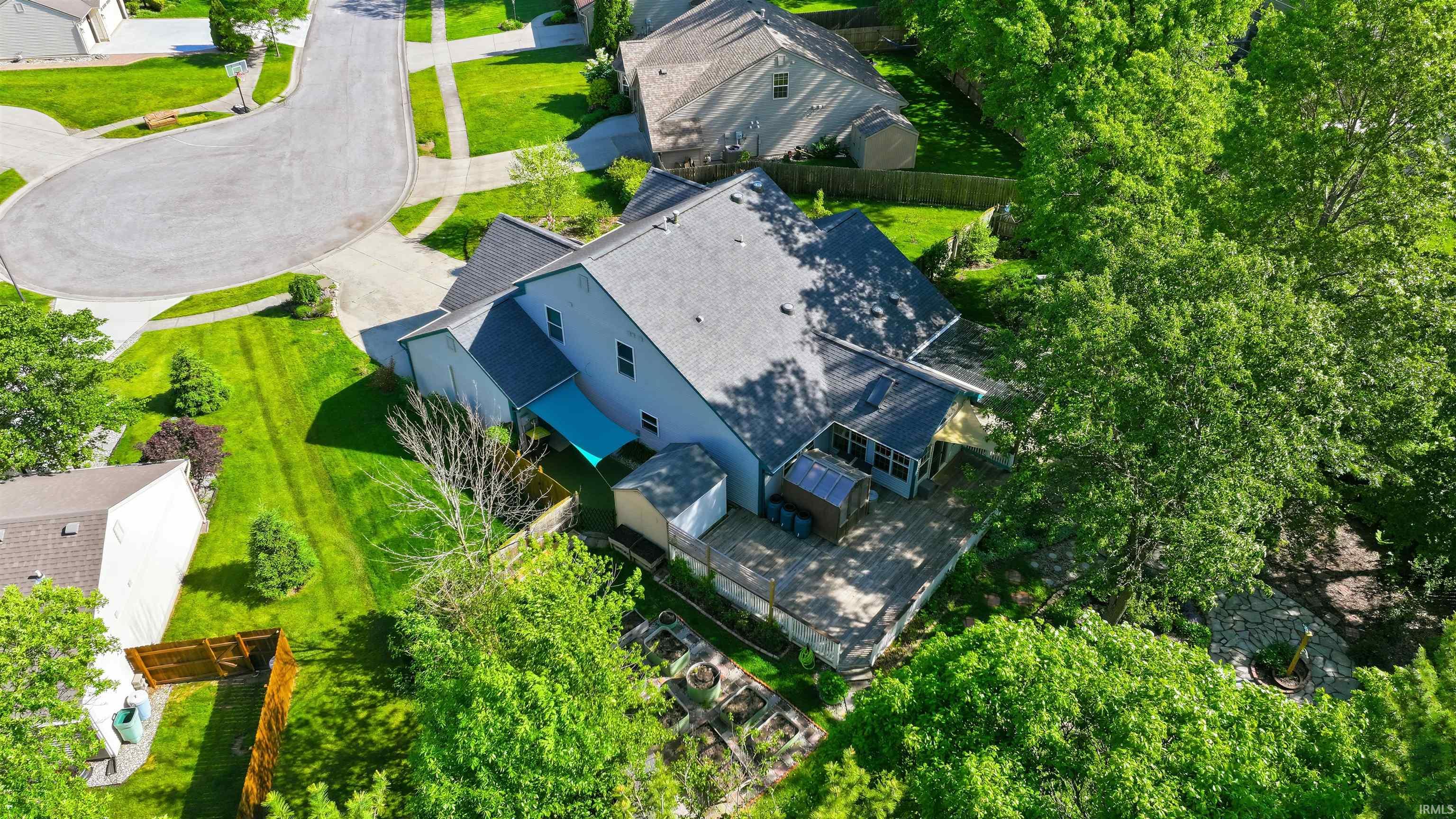 Expansive property featuring a multi-level structure with a patio, screened porch, garden beds, and mature trees
