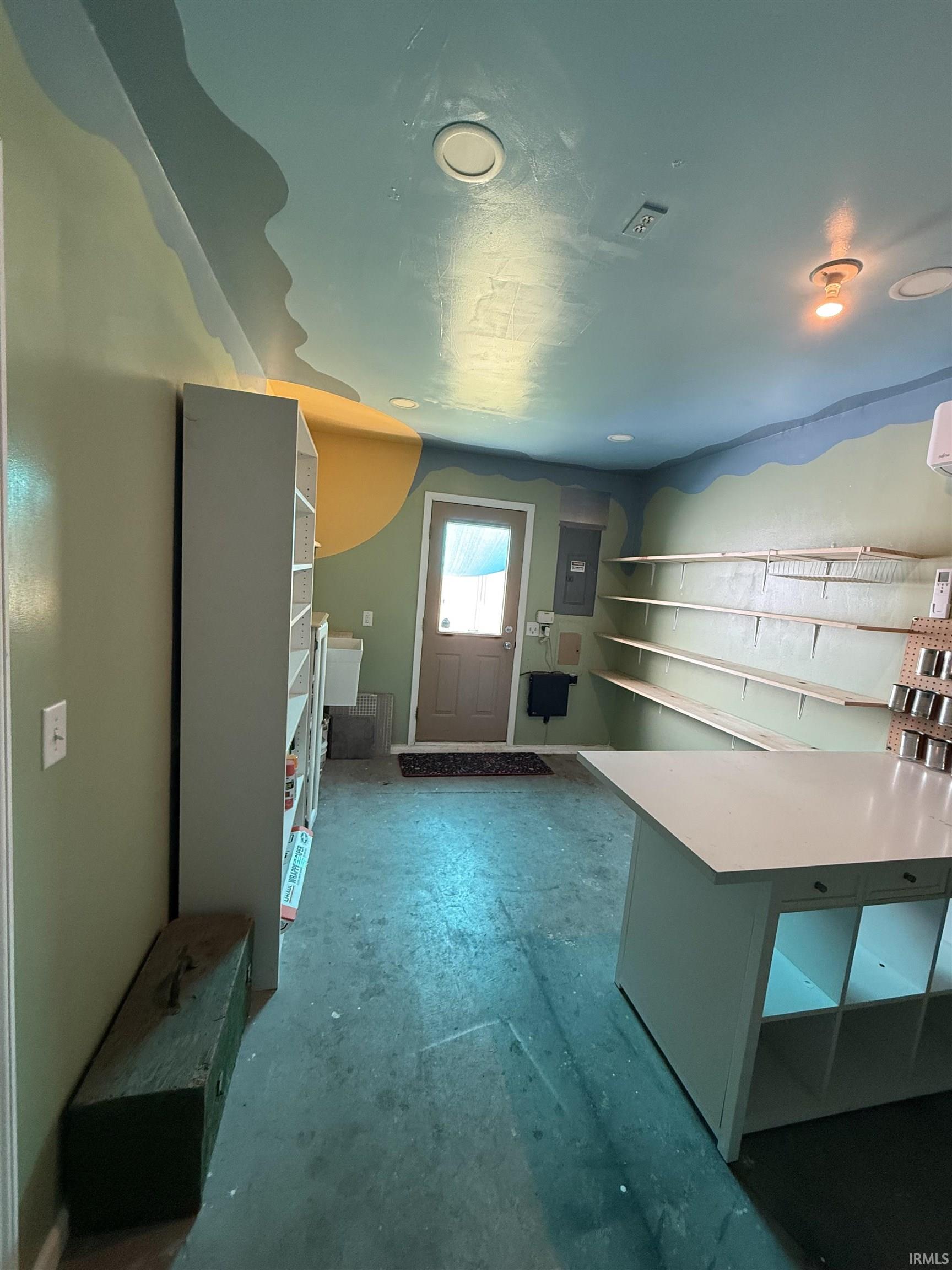 Versatile room featuring painted walls, a painted ceiling with recessed lighting, an exterior door, built-in shelving, and a large central island with integrated storage