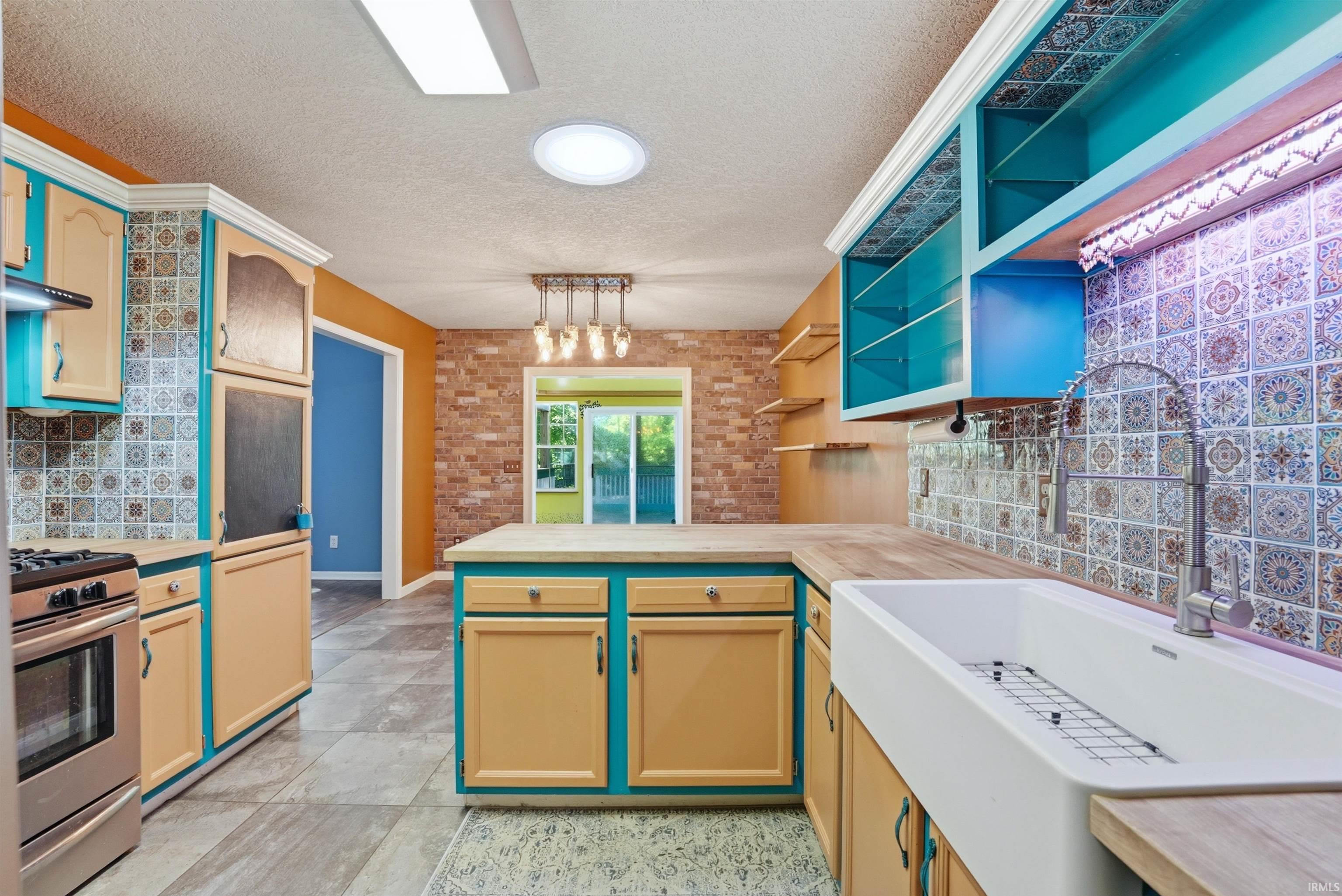 Kitchen featuring a farmhouse sink, wood-finish countertops, and patterned tile backsplash