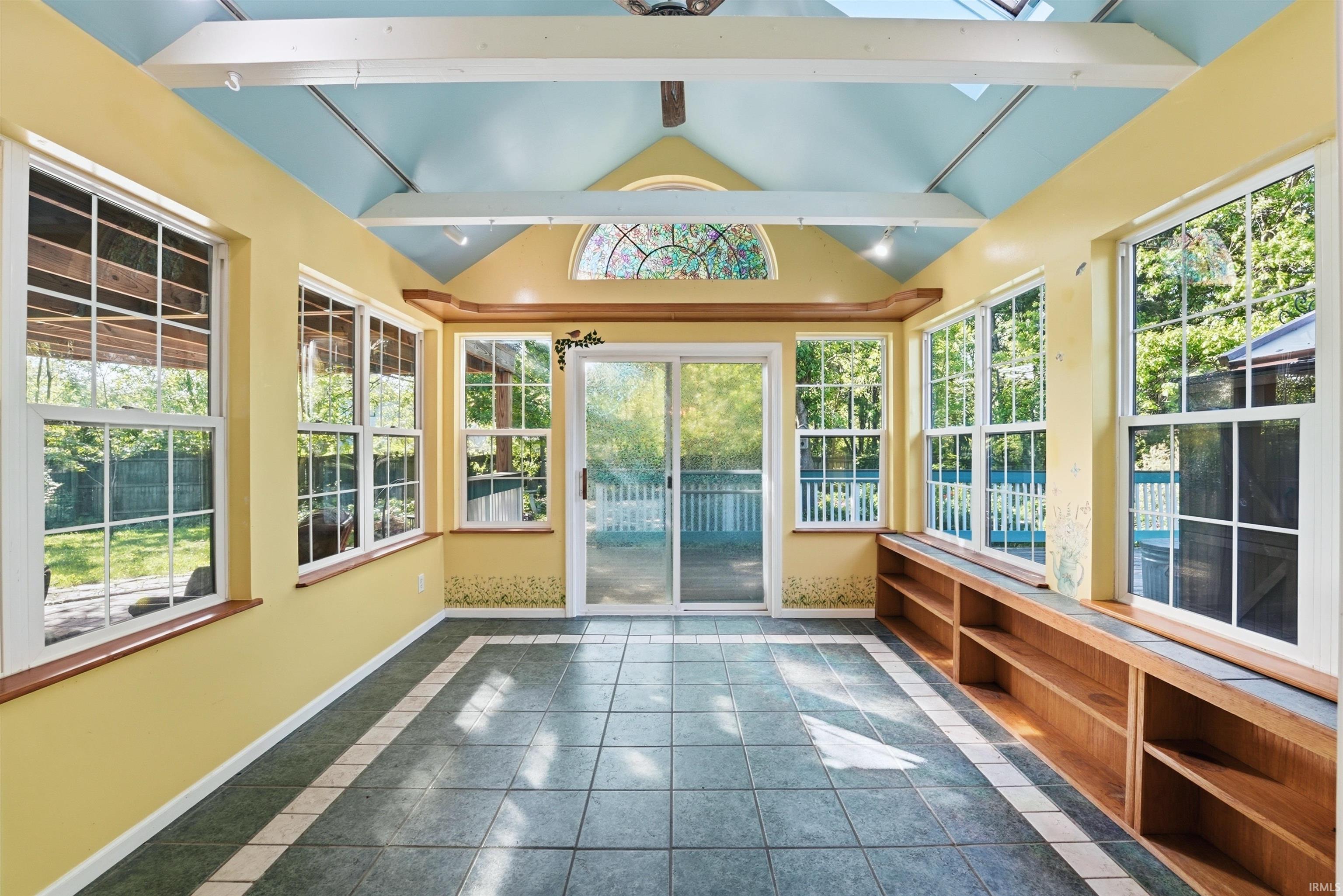 Sunroom featuring a vaulted ceiling with exposed beams, skylights, and a ceiling fan
