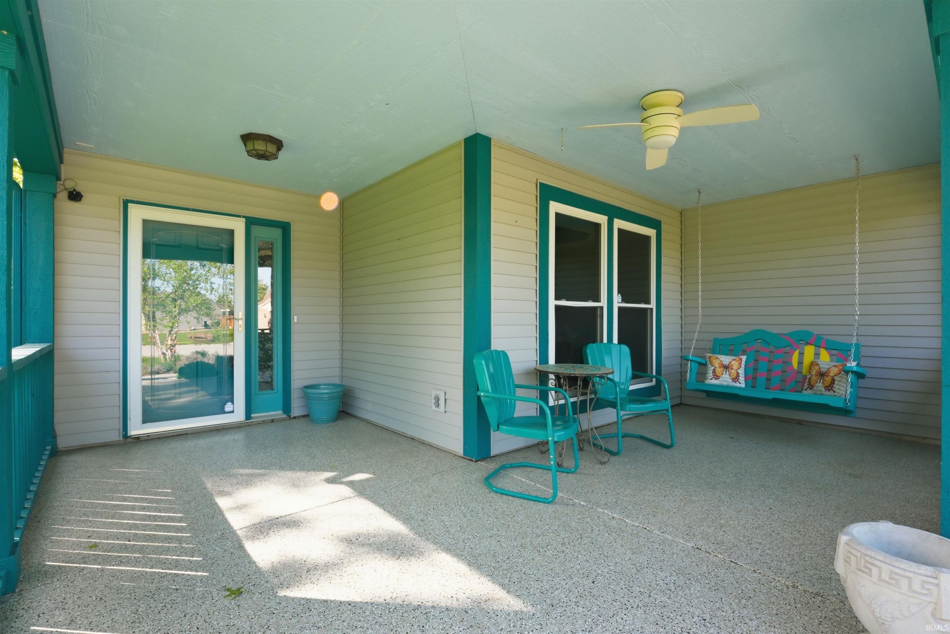 Covered porch featuring textured concrete flooring, a ceiling fan, and a light fixture