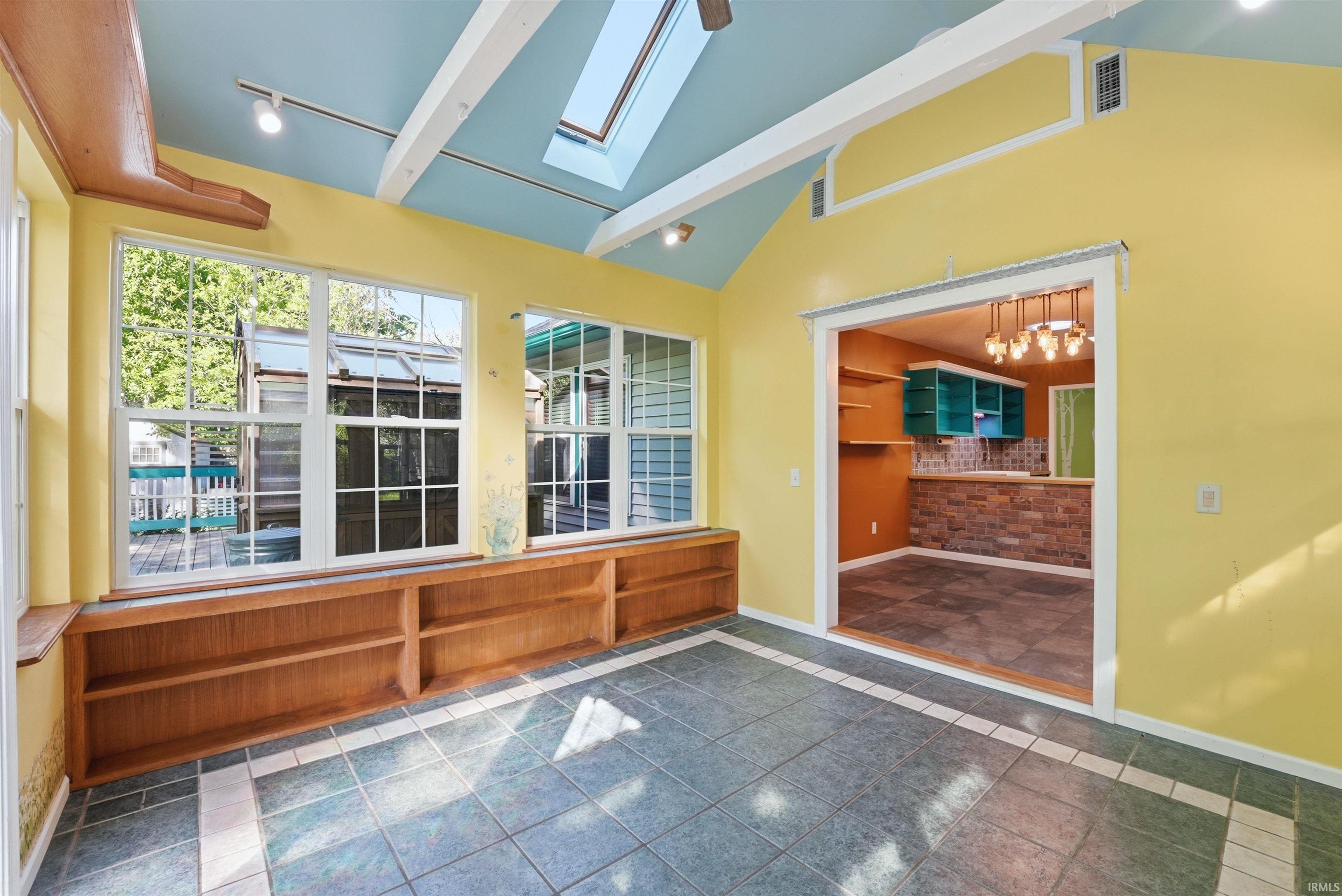 Sunroom featuring a skylight and vaulted ceiling with exposed beams