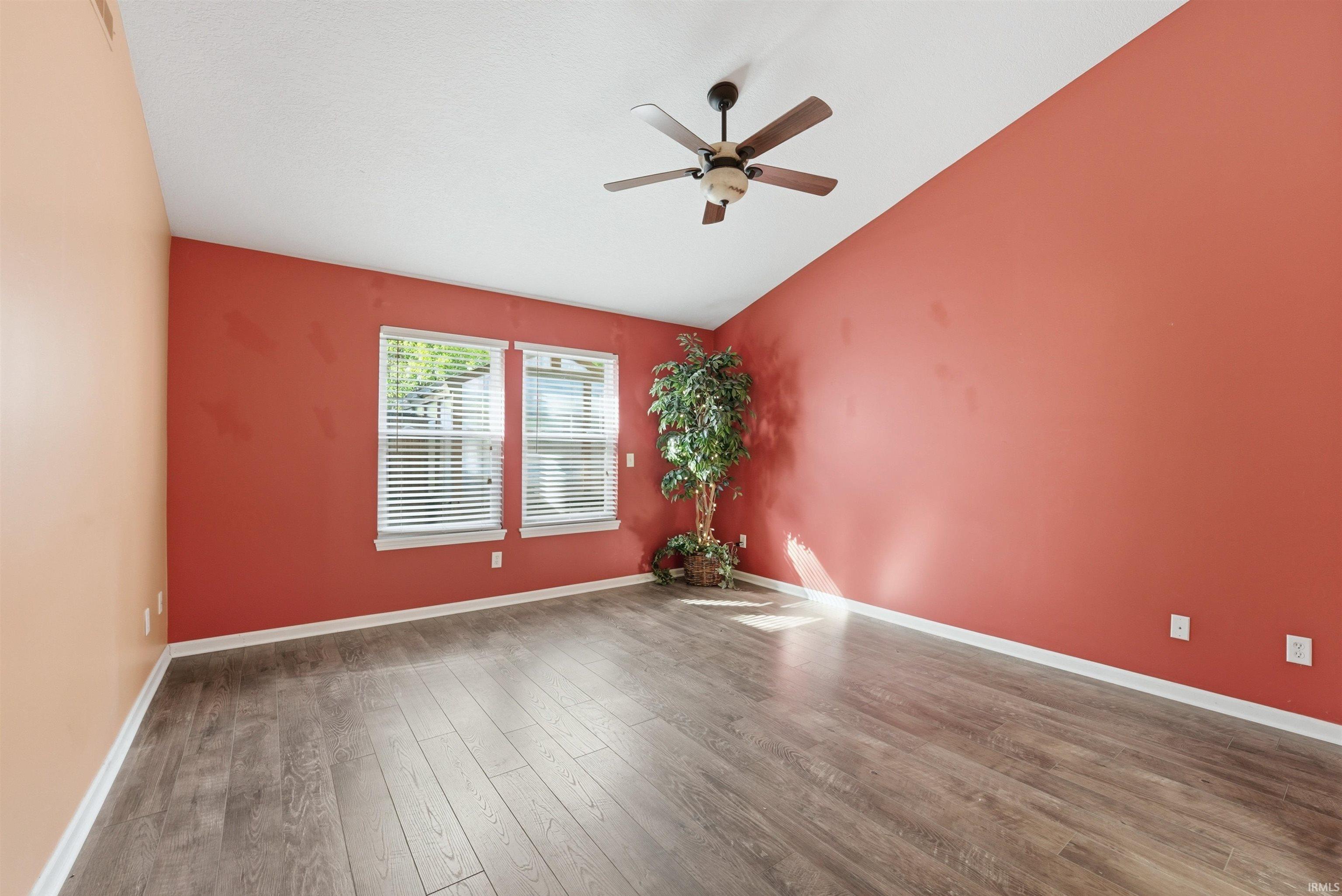 Spacious interior room featuring wood-finish flooring, a vaulted ceiling, and a ceiling fan
