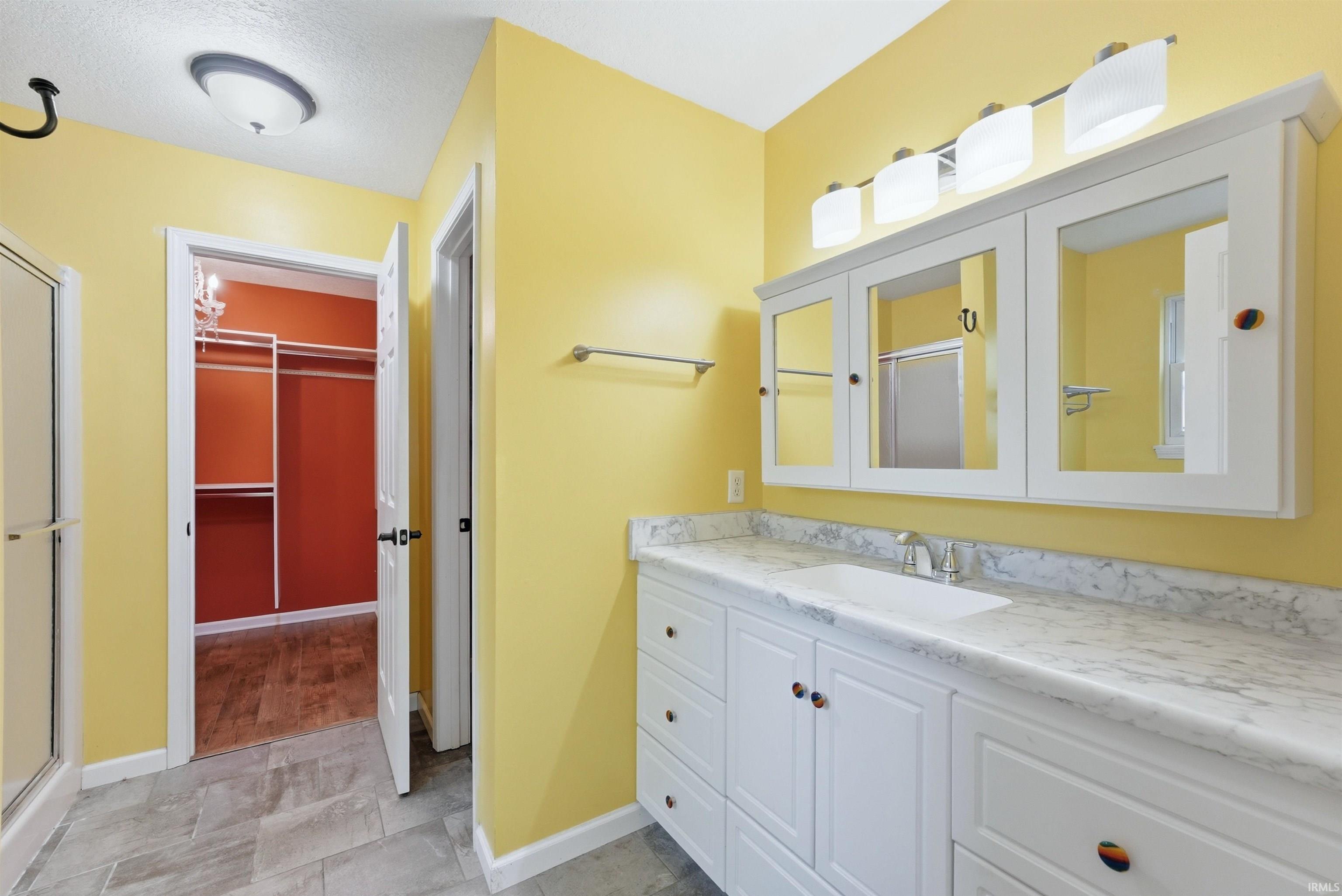 Bathroom featuring a double vanity with stone-finish countertop, white cabinetry, and integrated sink