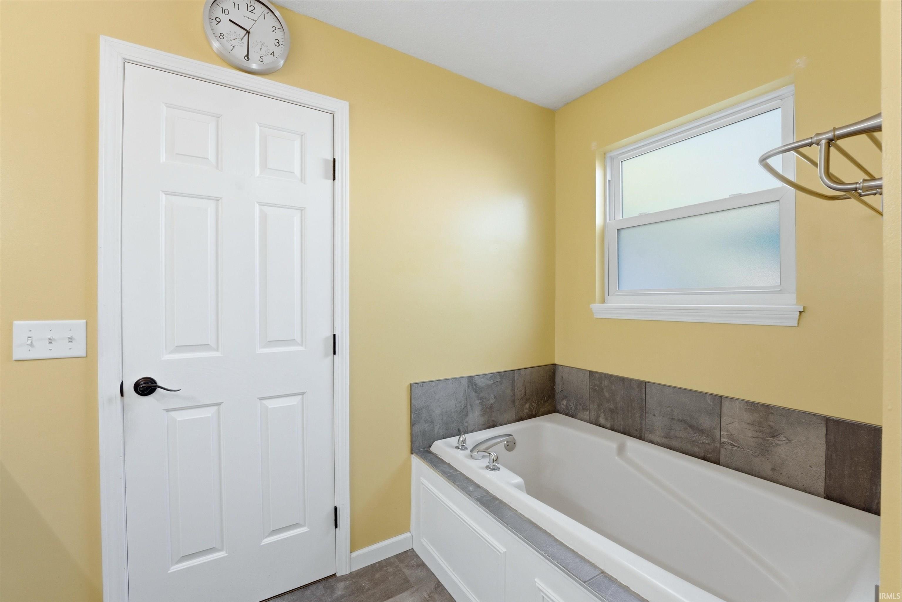 Recessed bathtub featuring a tiled surround and an adjacent window