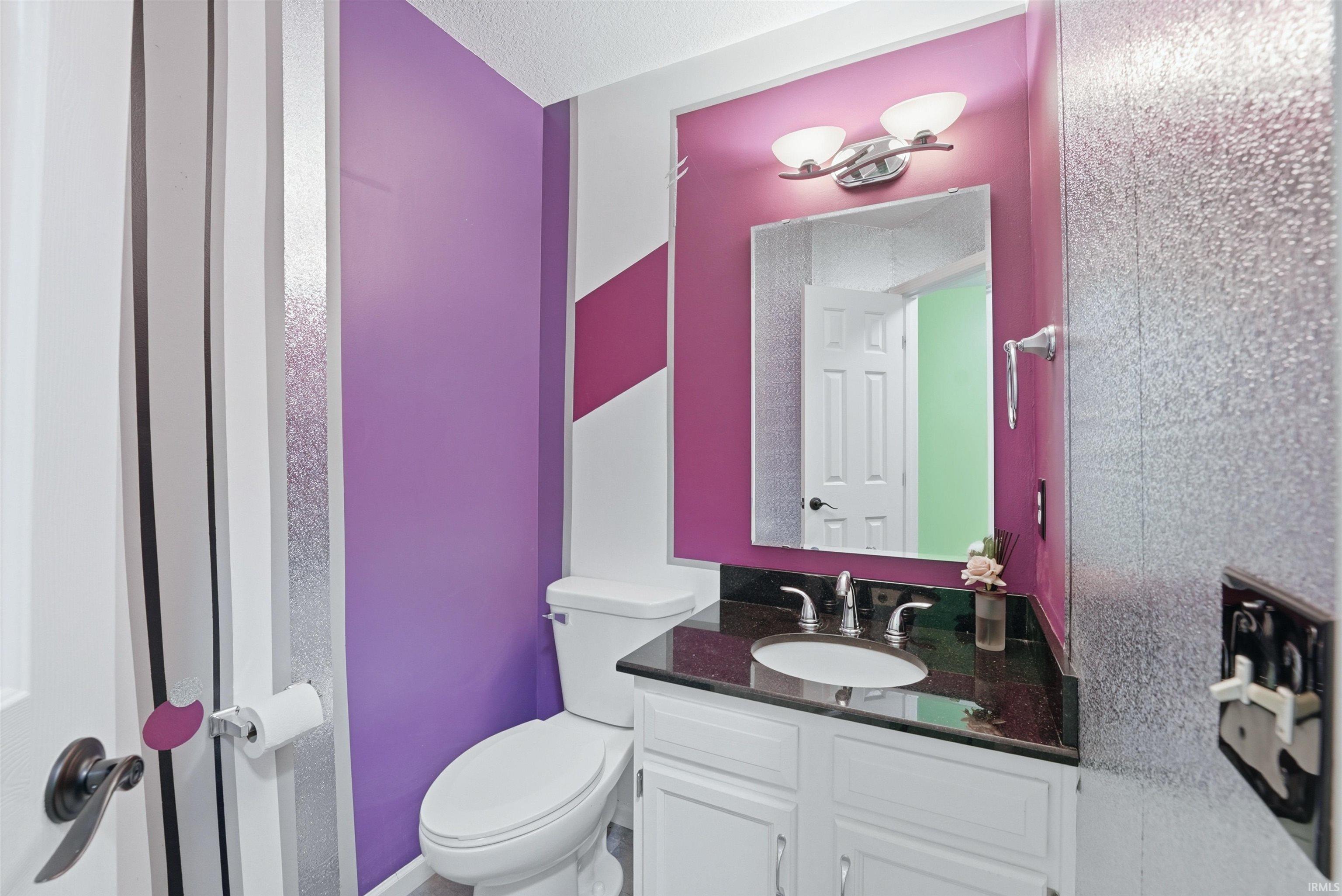 Bathroom featuring a white vanity with panel cabinetry, dark countertop, and an undermount sink