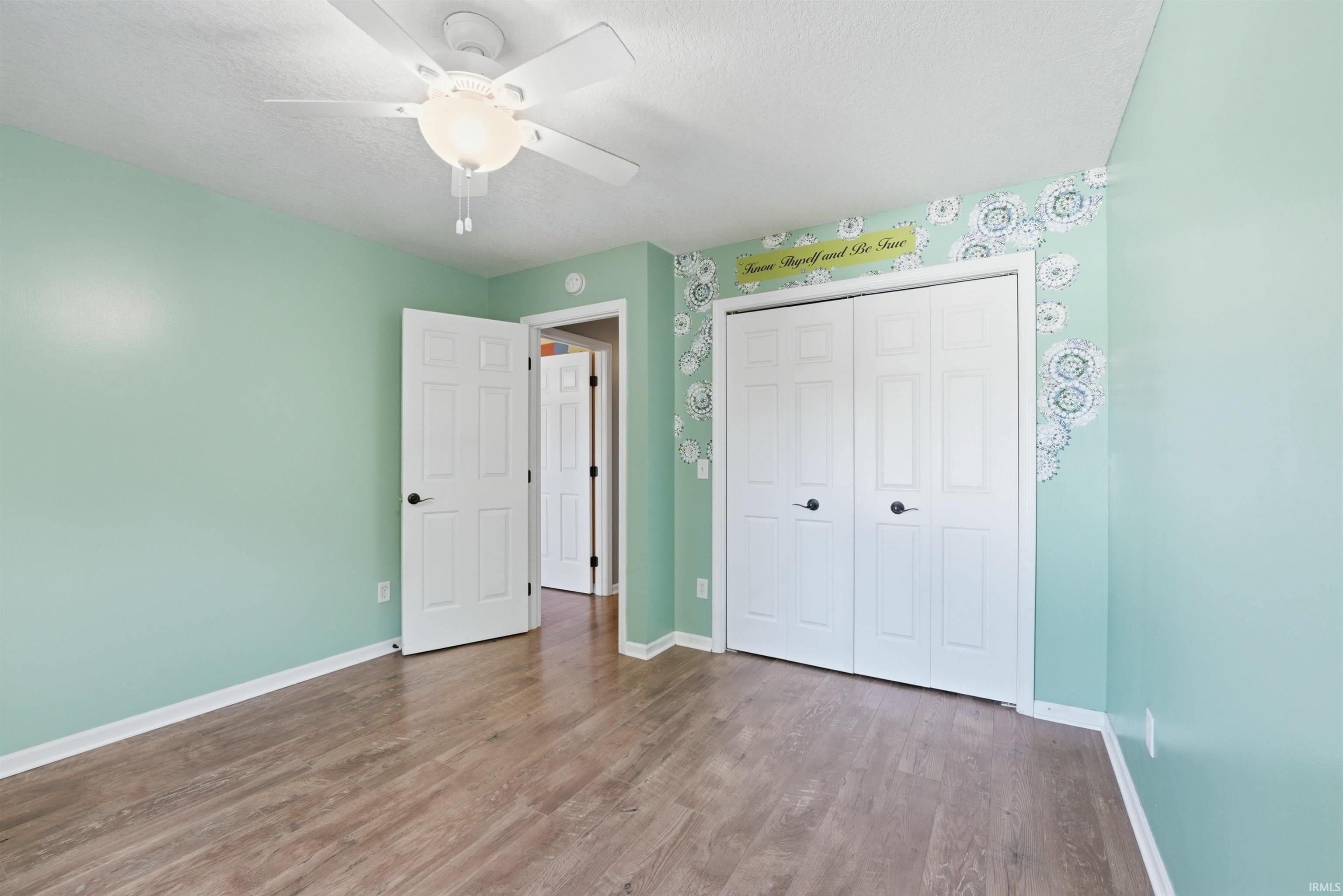 Spacious interior room featuring wood-finish flooring and light green wall tones