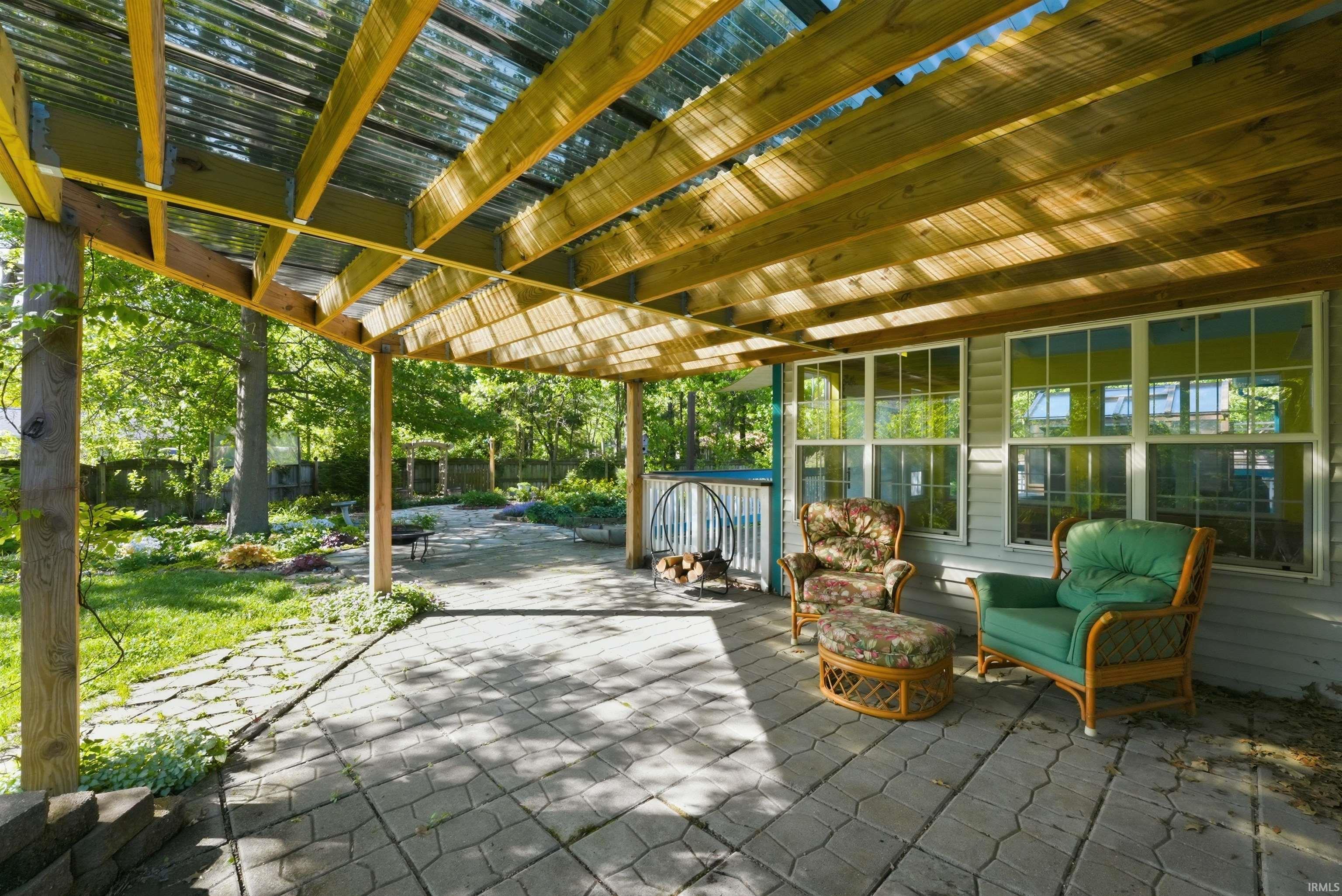 Covered patio featuring a corrugated translucent roof over exposed wood beams