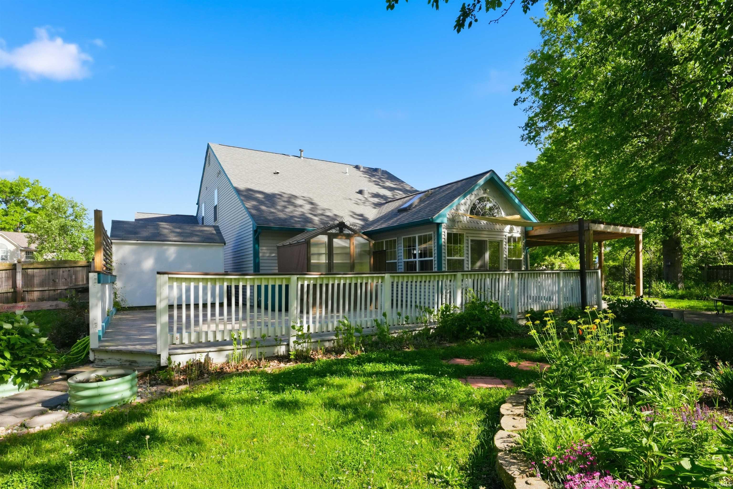 Spacious backyard featuring a multi-level deck, a sunroom extension with large windows, and a pergola
