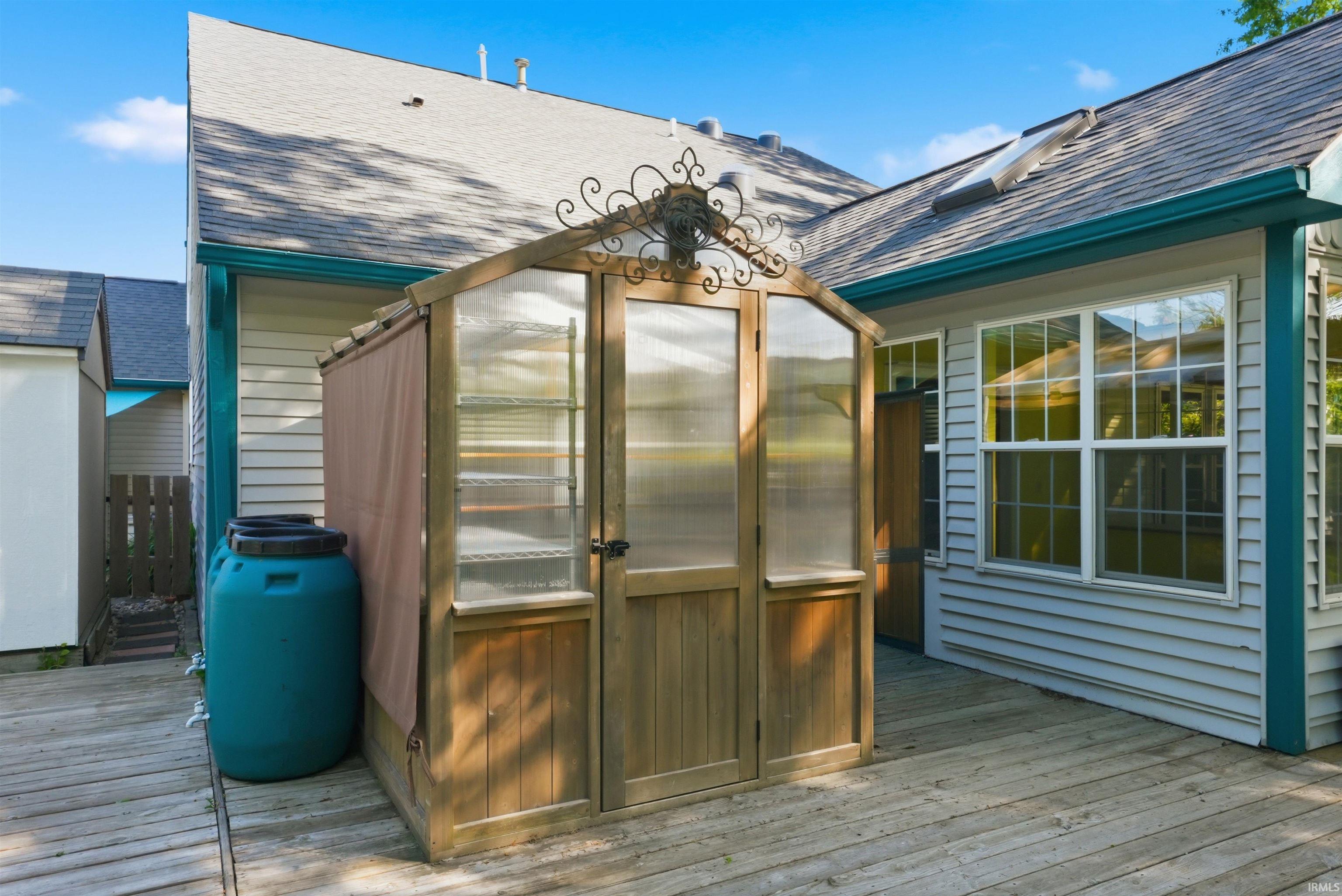 Expansive wood deck featuring a greenhouse with clear panels and an ornate metal accent