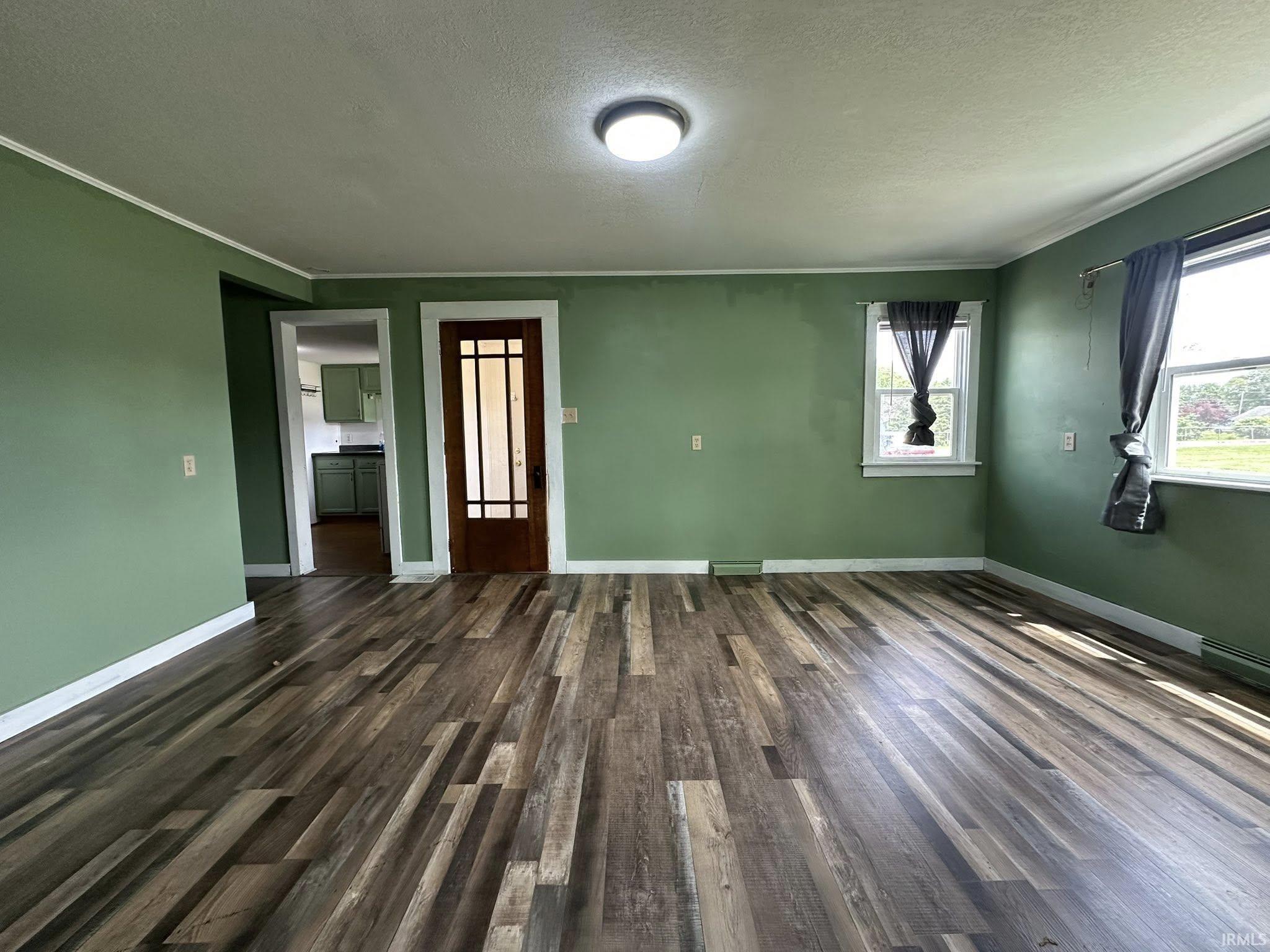 Wood-finish flooring throughout a spacious room with multiple windows