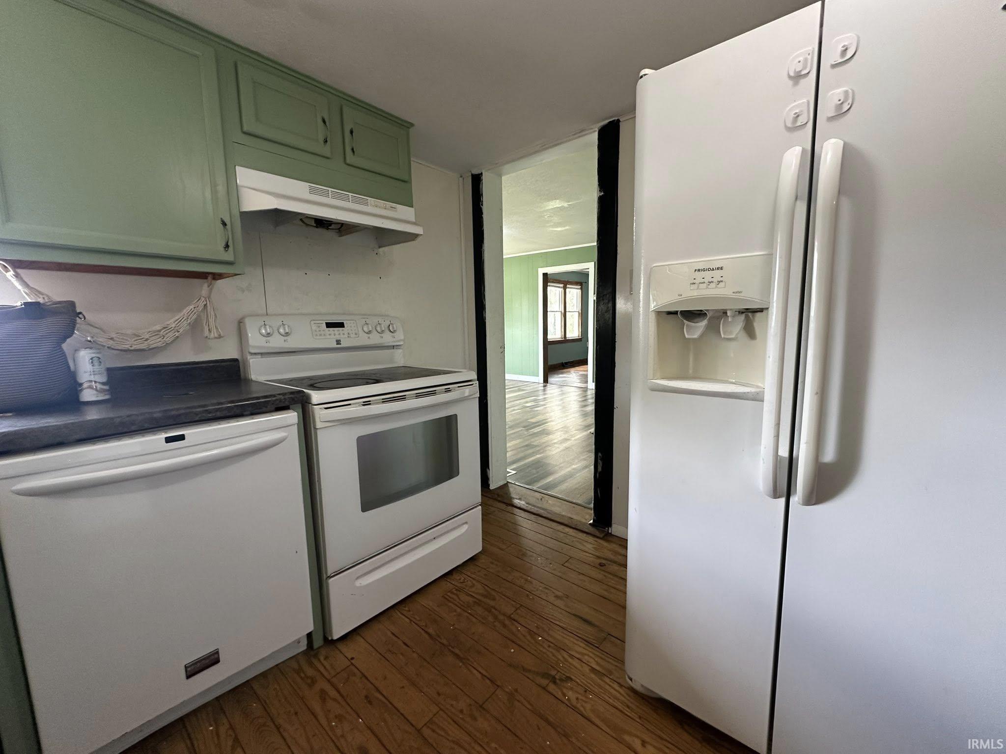 Kitchen featuring wood-finish flooring, white appliances, dark countertops, and painted cabinetry