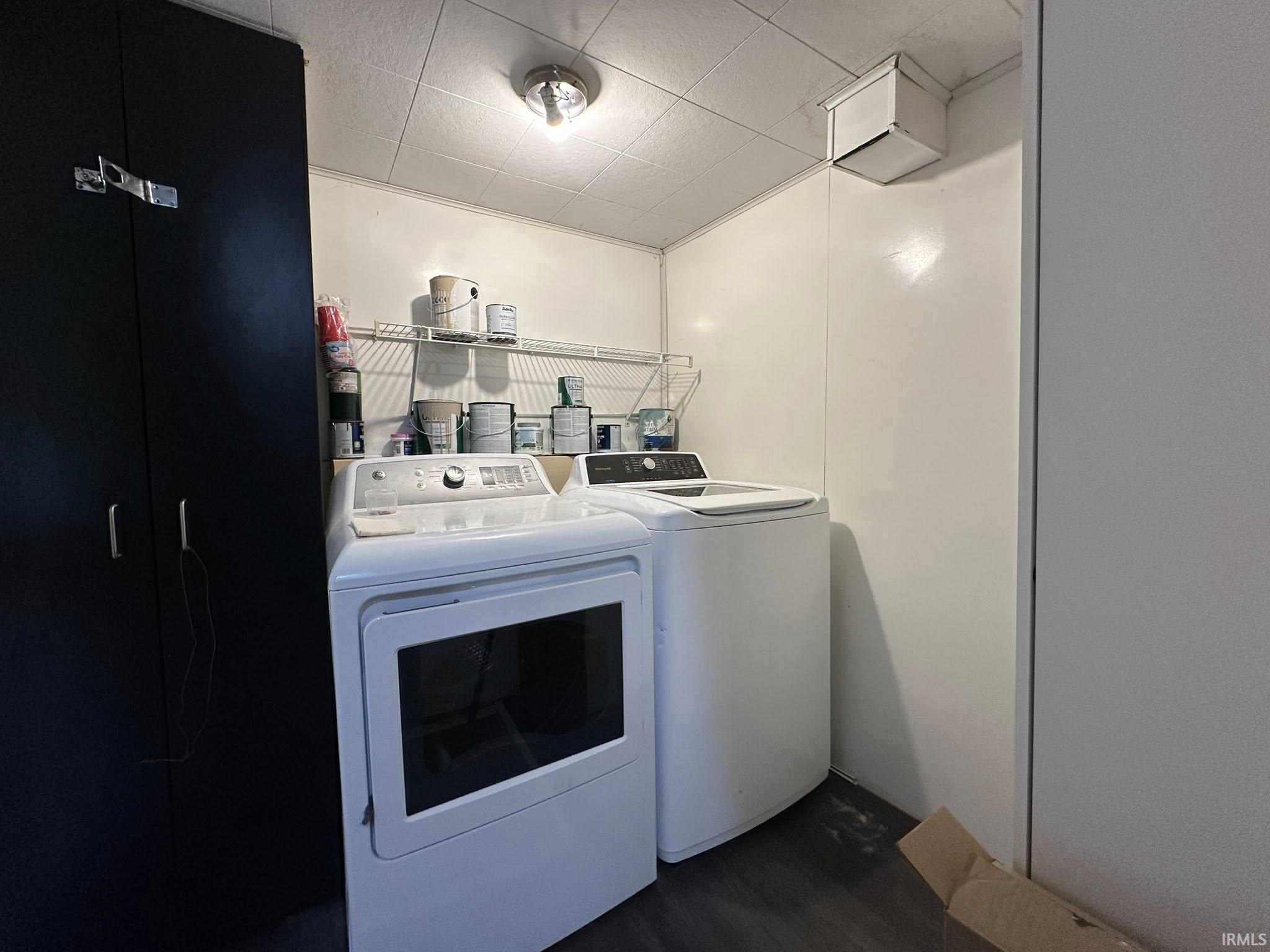 Dedicated laundry area featuring a dark wood-finish storage cabinet, wire shelving, ceiling-mounted light fixture, and textured ceiling
