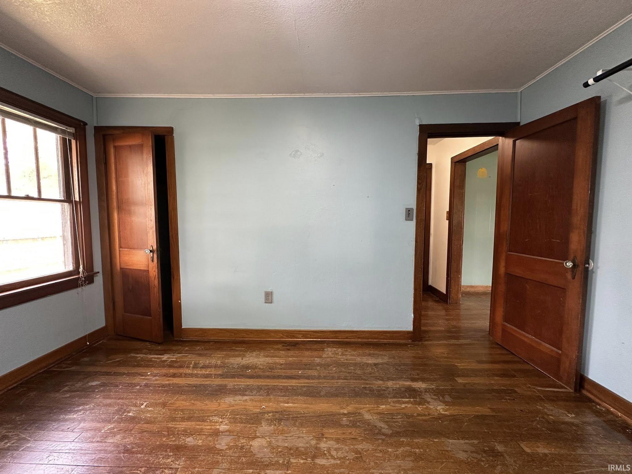 Interior space featuring wood-finish flooring, light blue walls, and multiple solid wood doors with traditional hardware