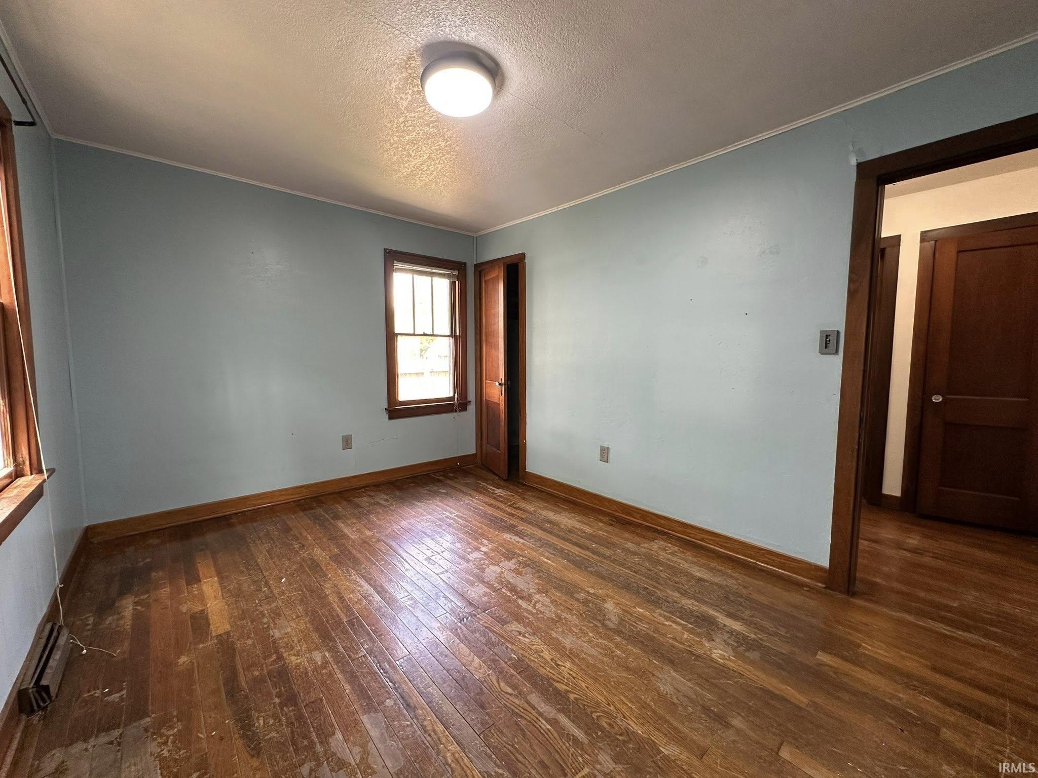 Hardwood flooring throughout, complemented by two windows with wood trim