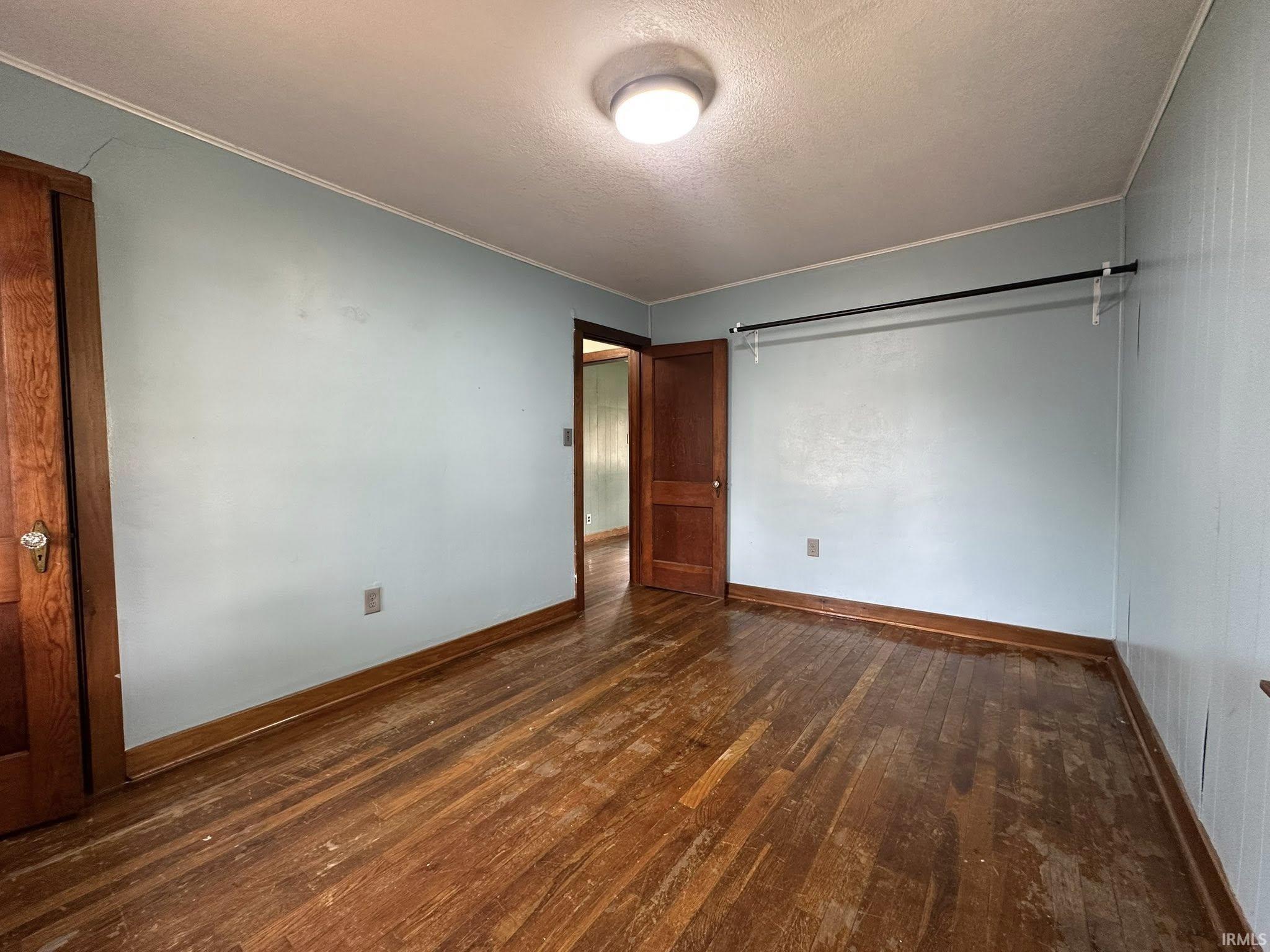 Room featuring wood-finish flooring, light blue wall paint, and a mounted ceiling light fixture