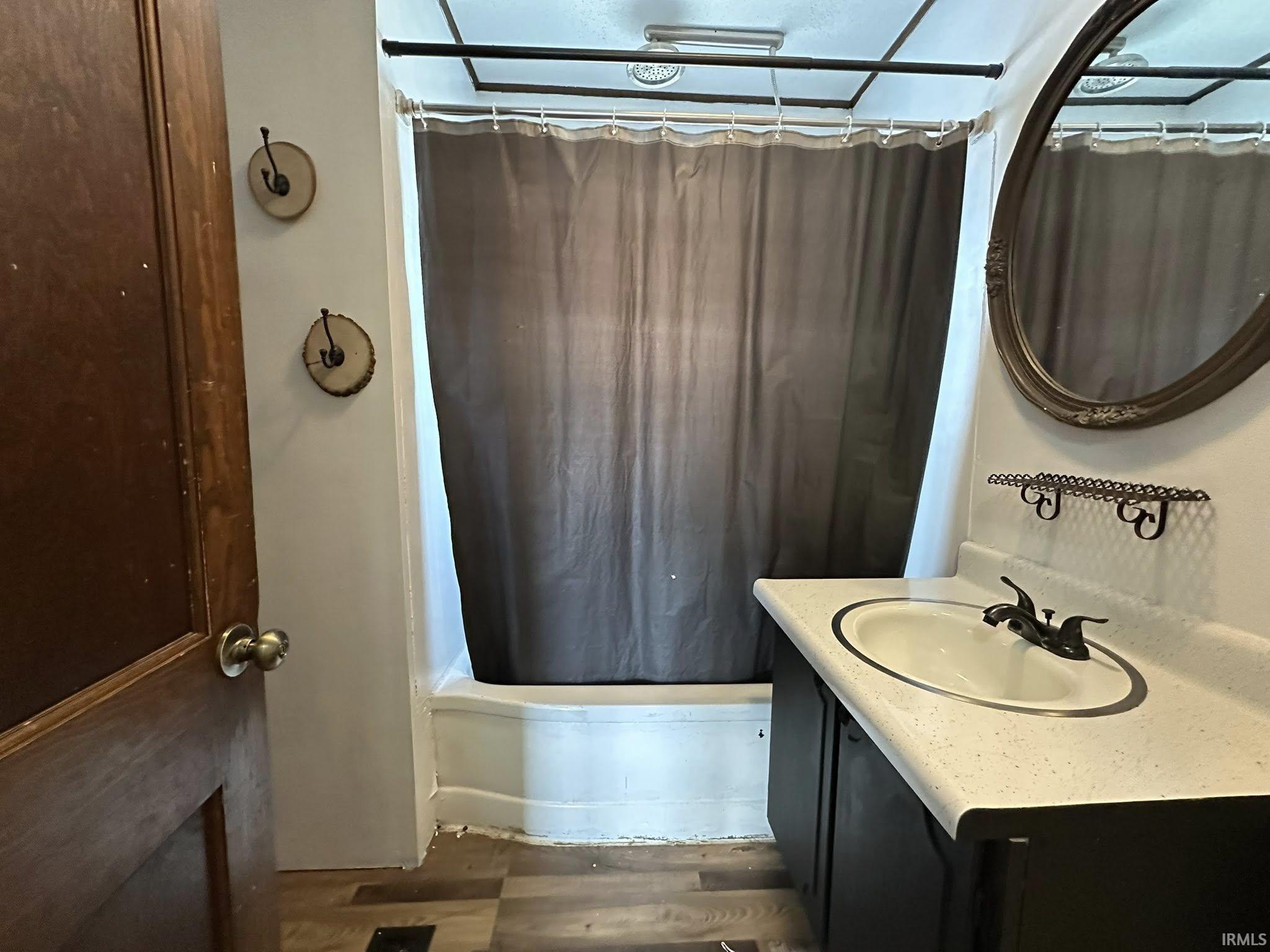 Bathroom featuring a built-in tub with shower, single vanity with integrated sink, and an ornate framed mirror