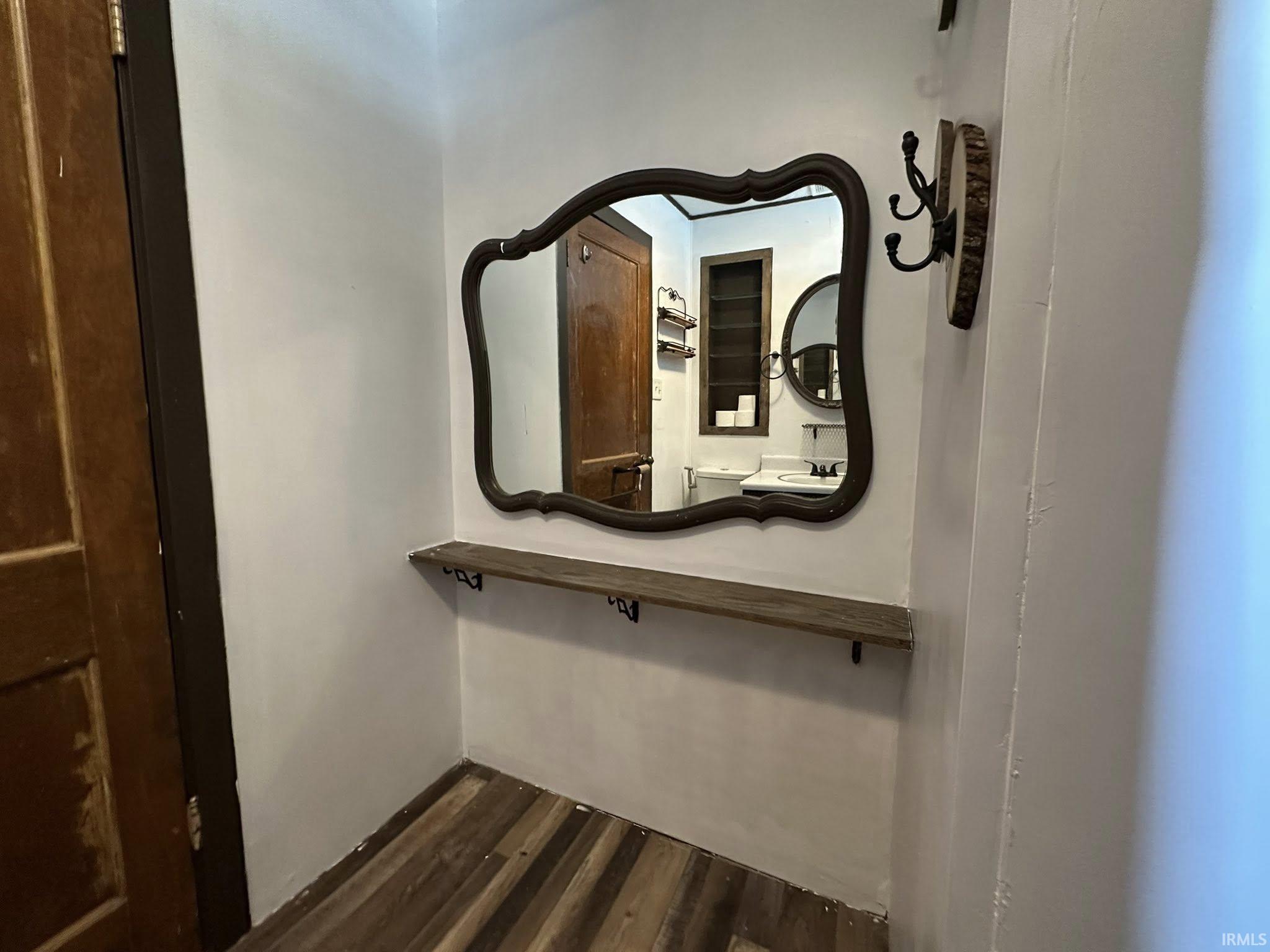 Decorative wall mirror with an ornate frame positioned above a floating wood-finish shelf