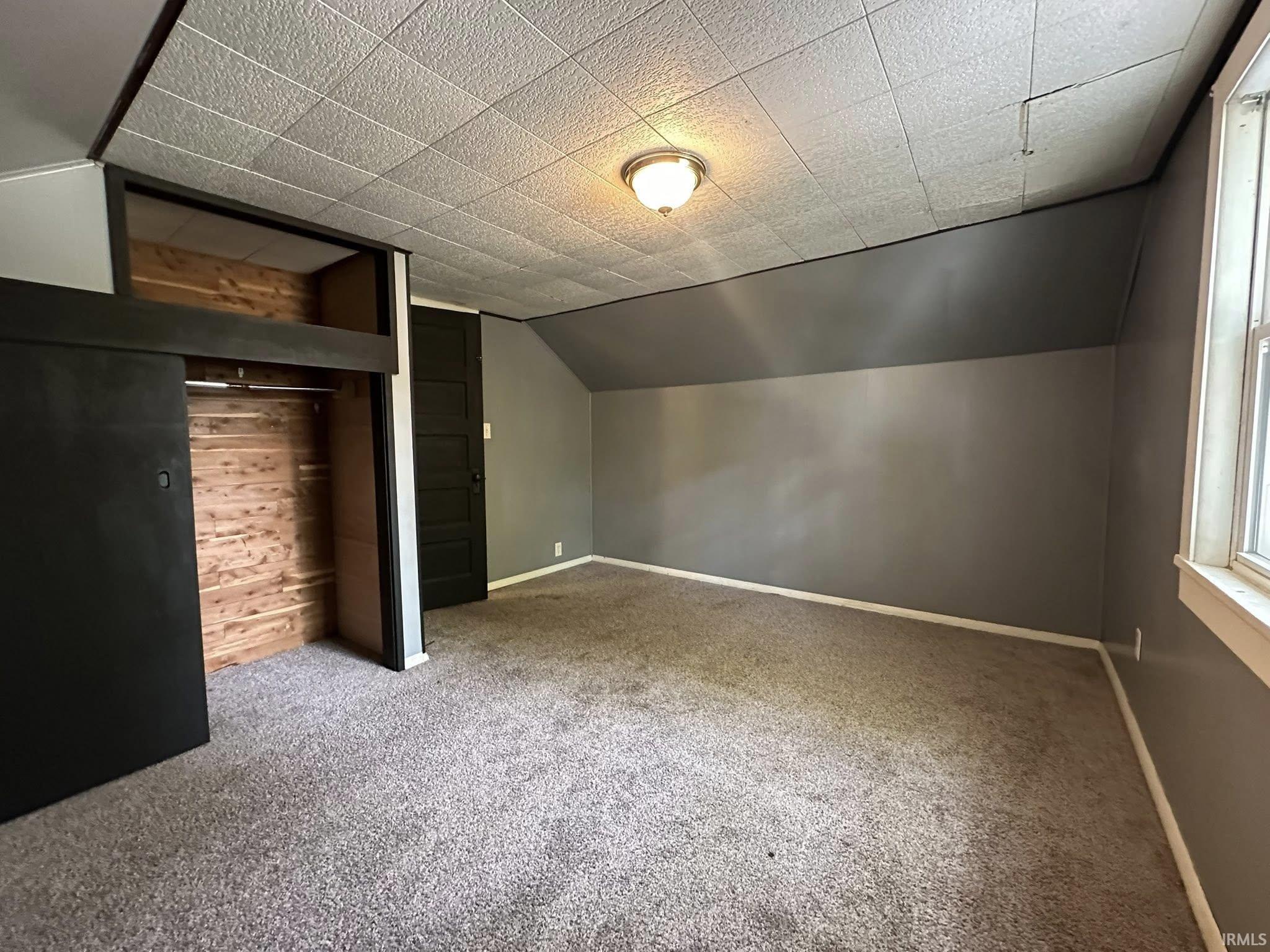 Room featuring gray carpeting and sloped walls