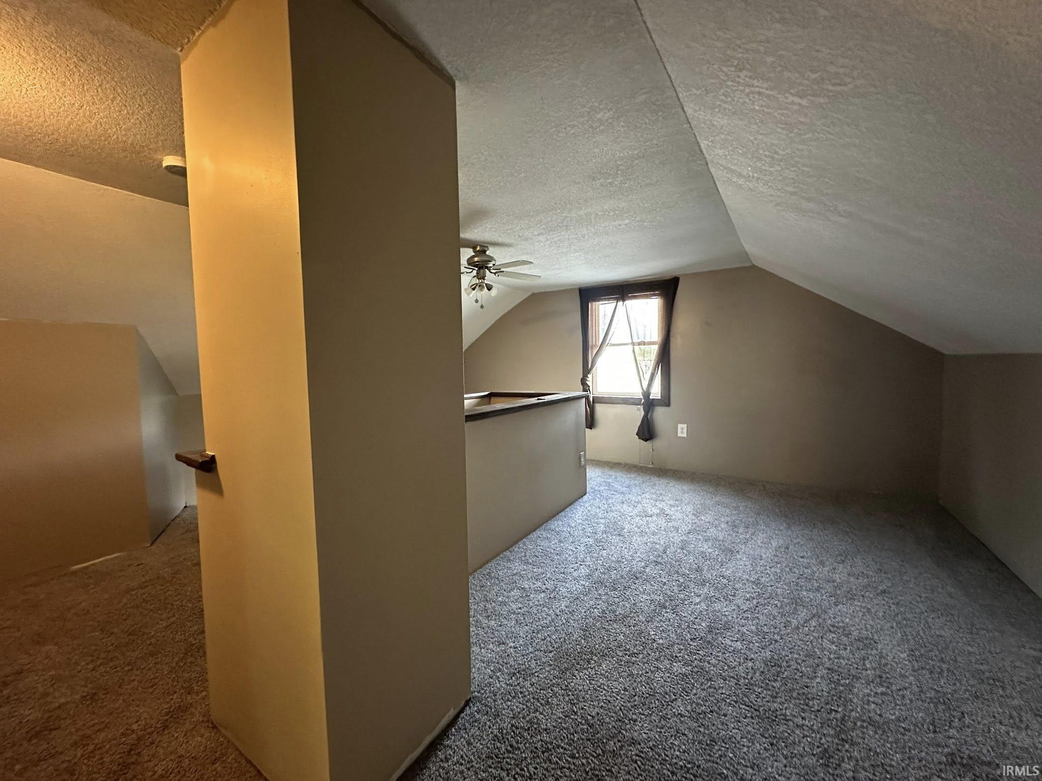 Loft space with angled ceilings and a window