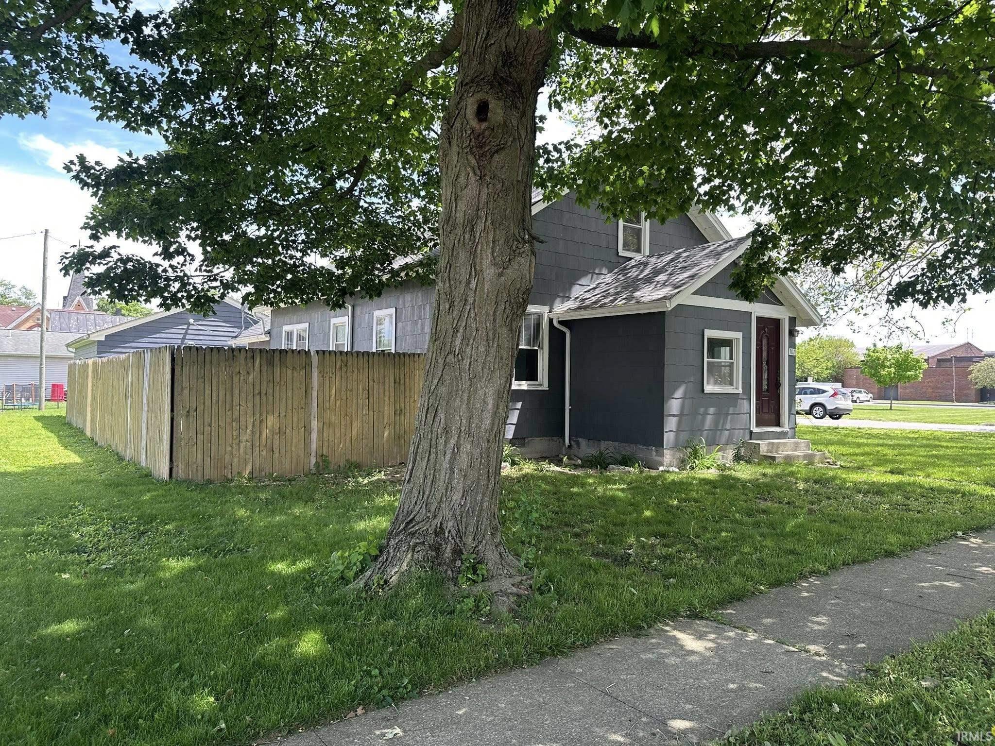 Gray shingle-sided home featuring a covered front entry with a wood-paneled door