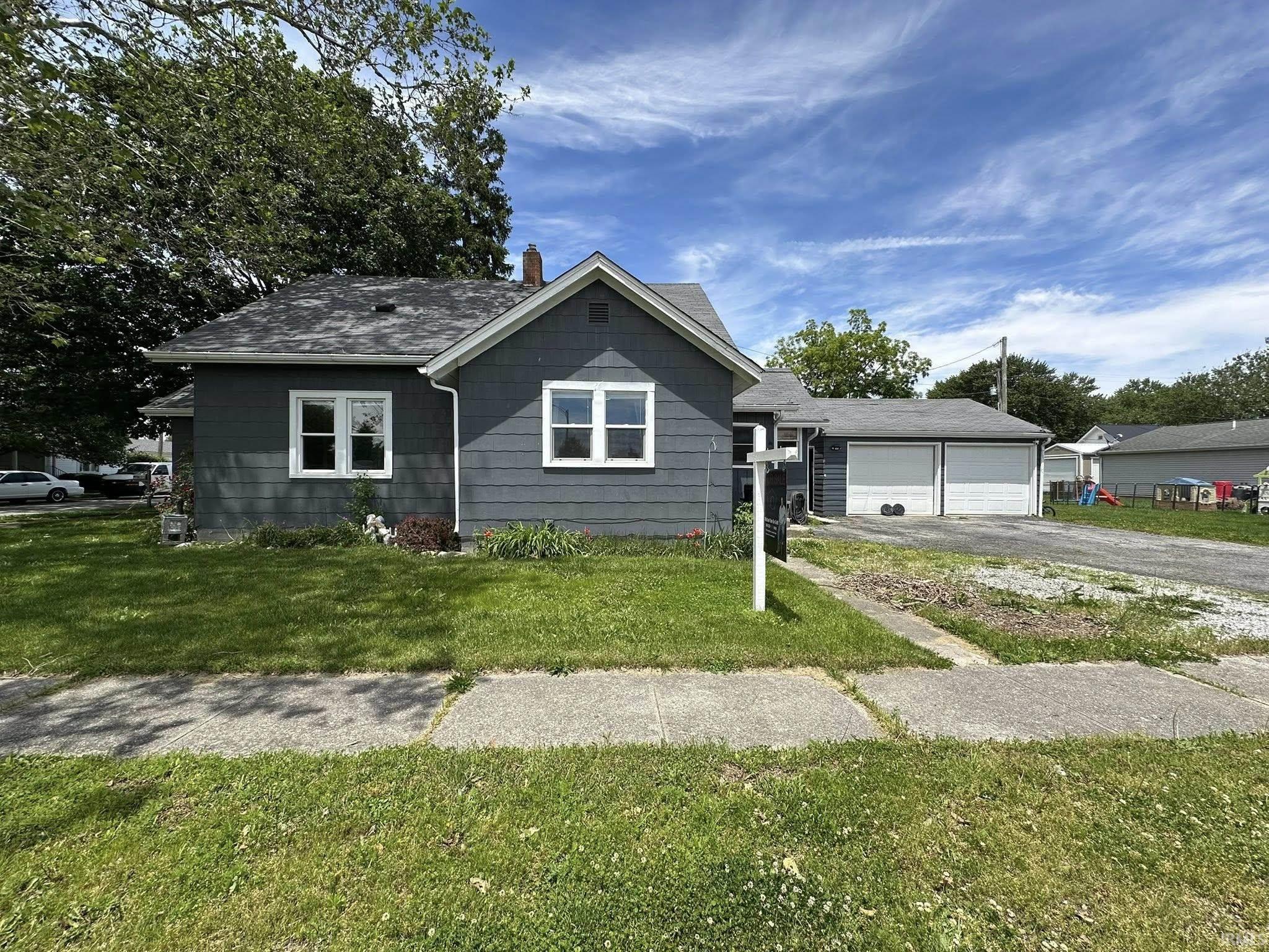 Single-story home featuring dark gray siding, white trim windows, and a shingle roof