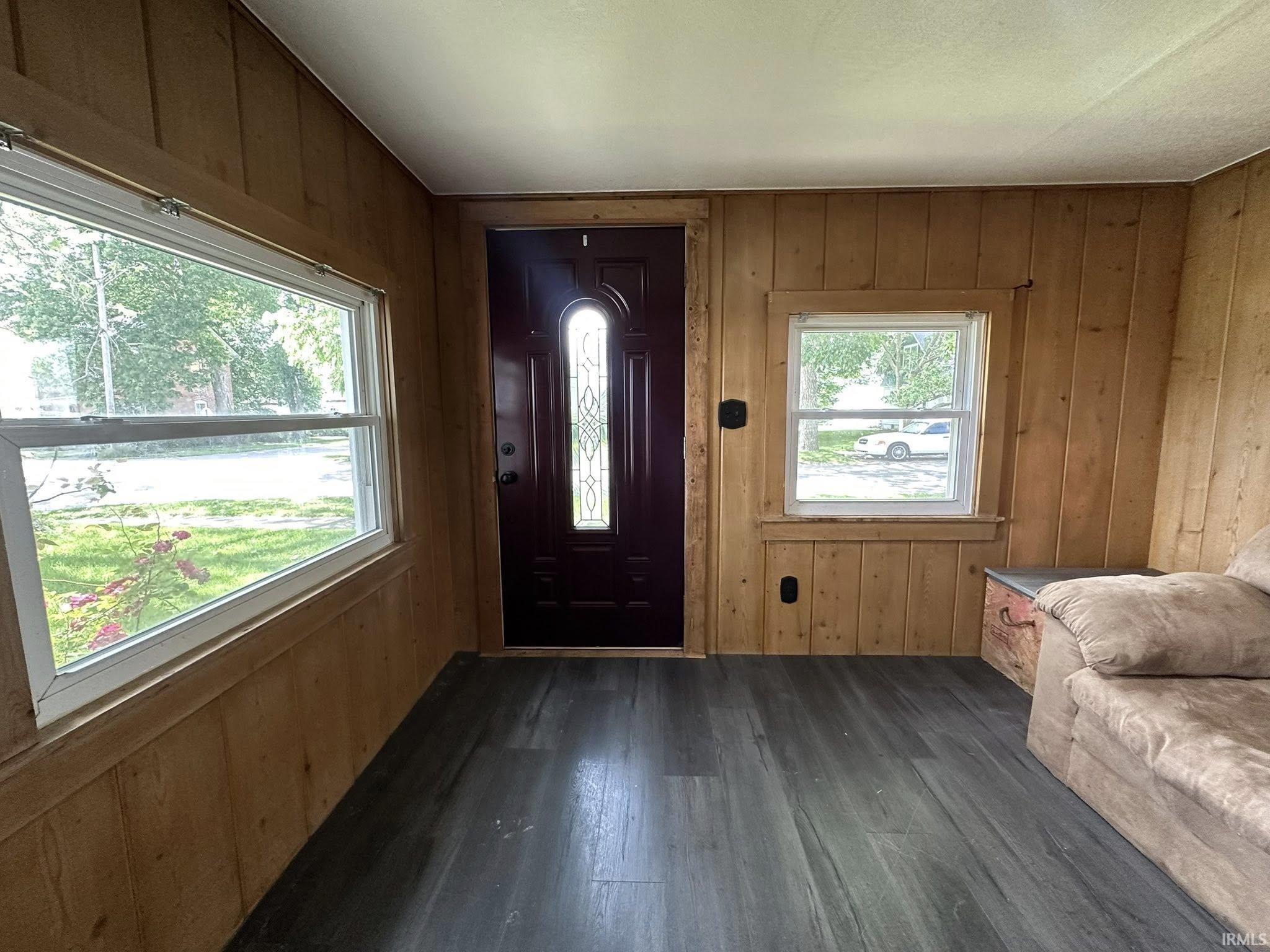 Entryway featuring wood paneling, dark wood-finish flooring, and a door with decorative glass inserts