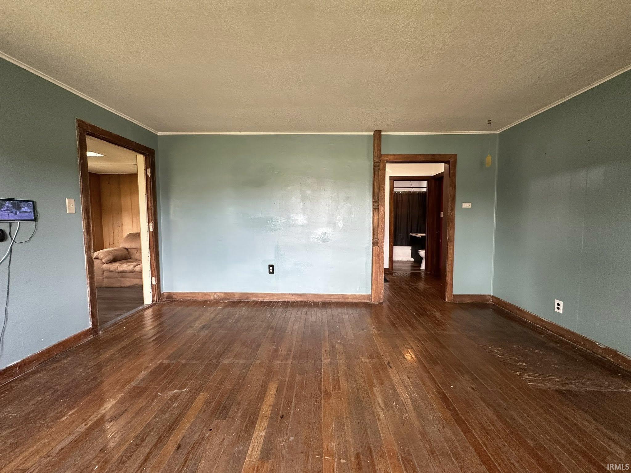 Hardwood flooring throughout the room with light blue wall paint and contrasting dark wood trim