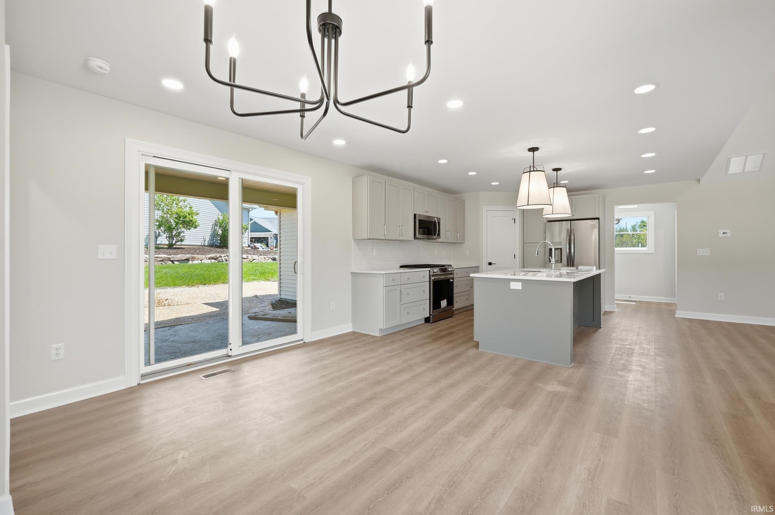 Open-concept living space featuring wood-finish flooring, recessed lighting, and a contemporary chandelier