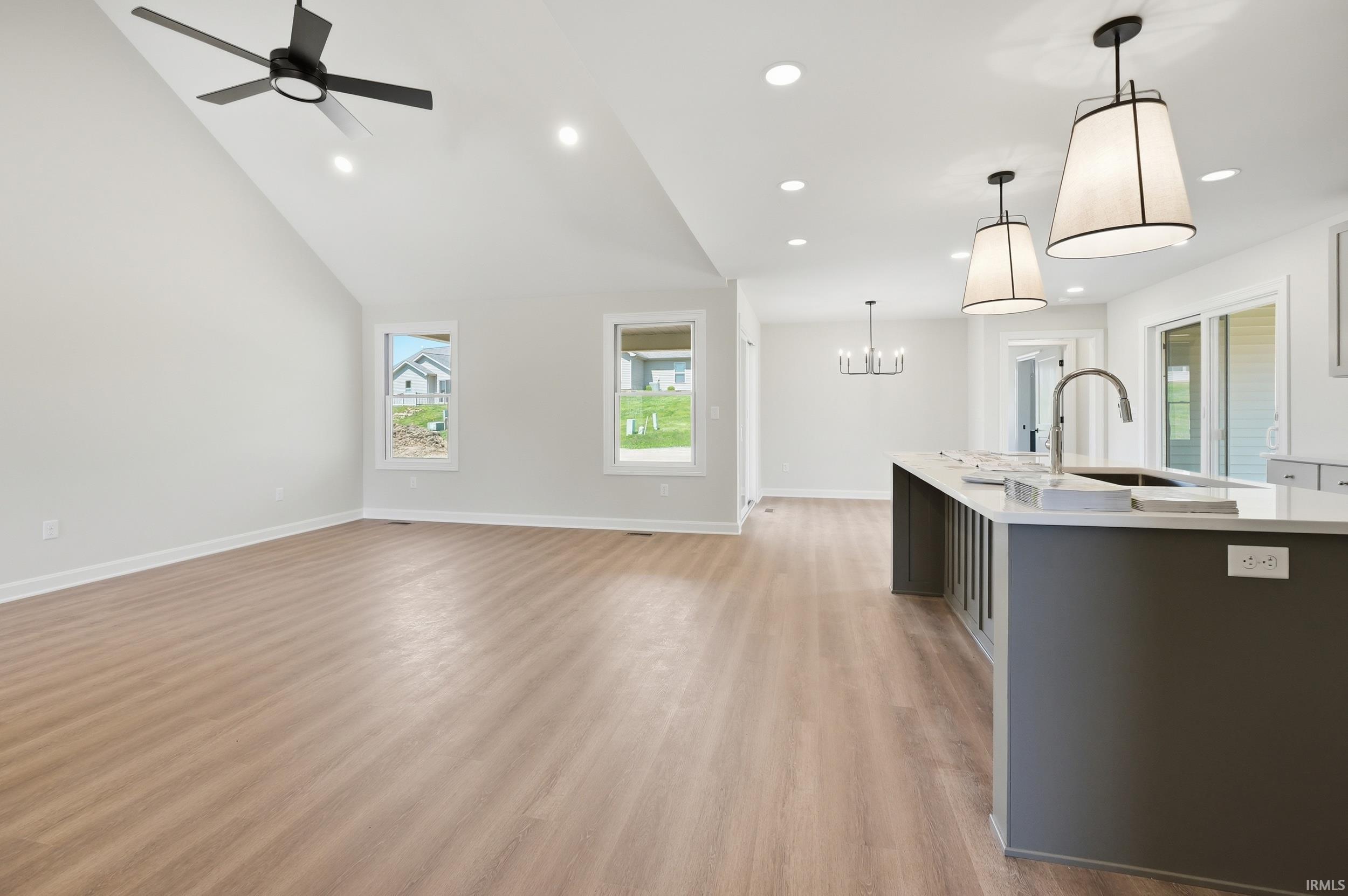 Open-concept living space featuring wood-finish flooring, vaulted ceiling, and recessed lighting