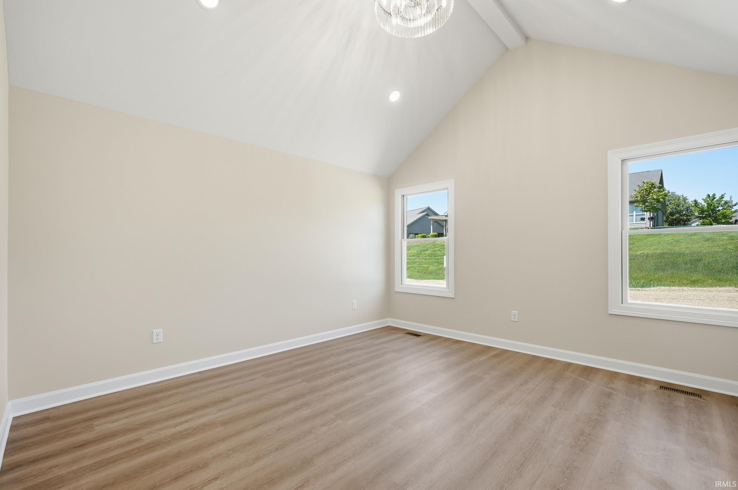 Vaulted ceiling room featuring wood-finish flooring, recessed lighting, and a decorative ceiling fixture